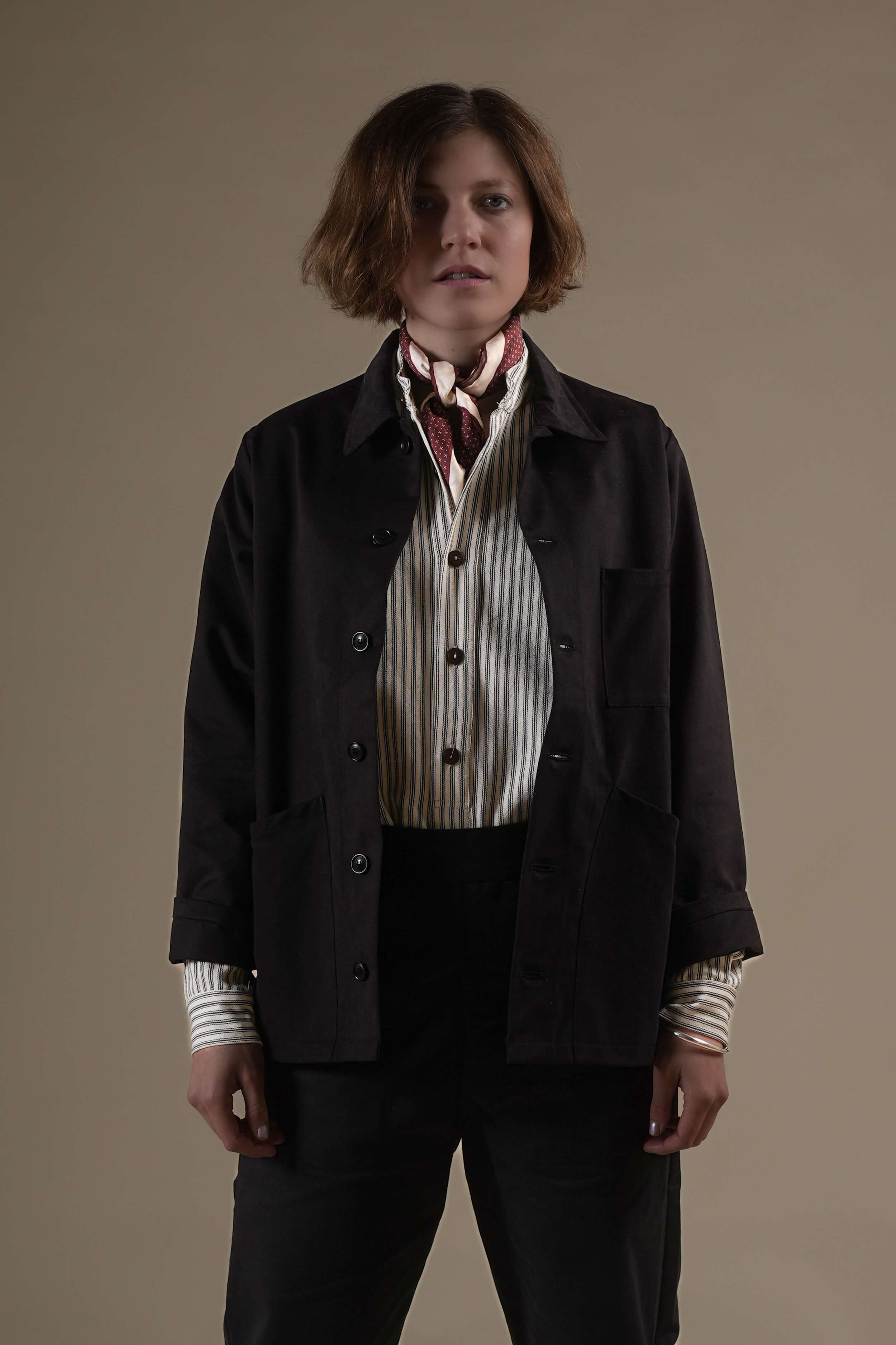 Woman wears Carrier Company Norfolk Work jacket in Black With Work Trouser In Black & Ticking Work Shirt