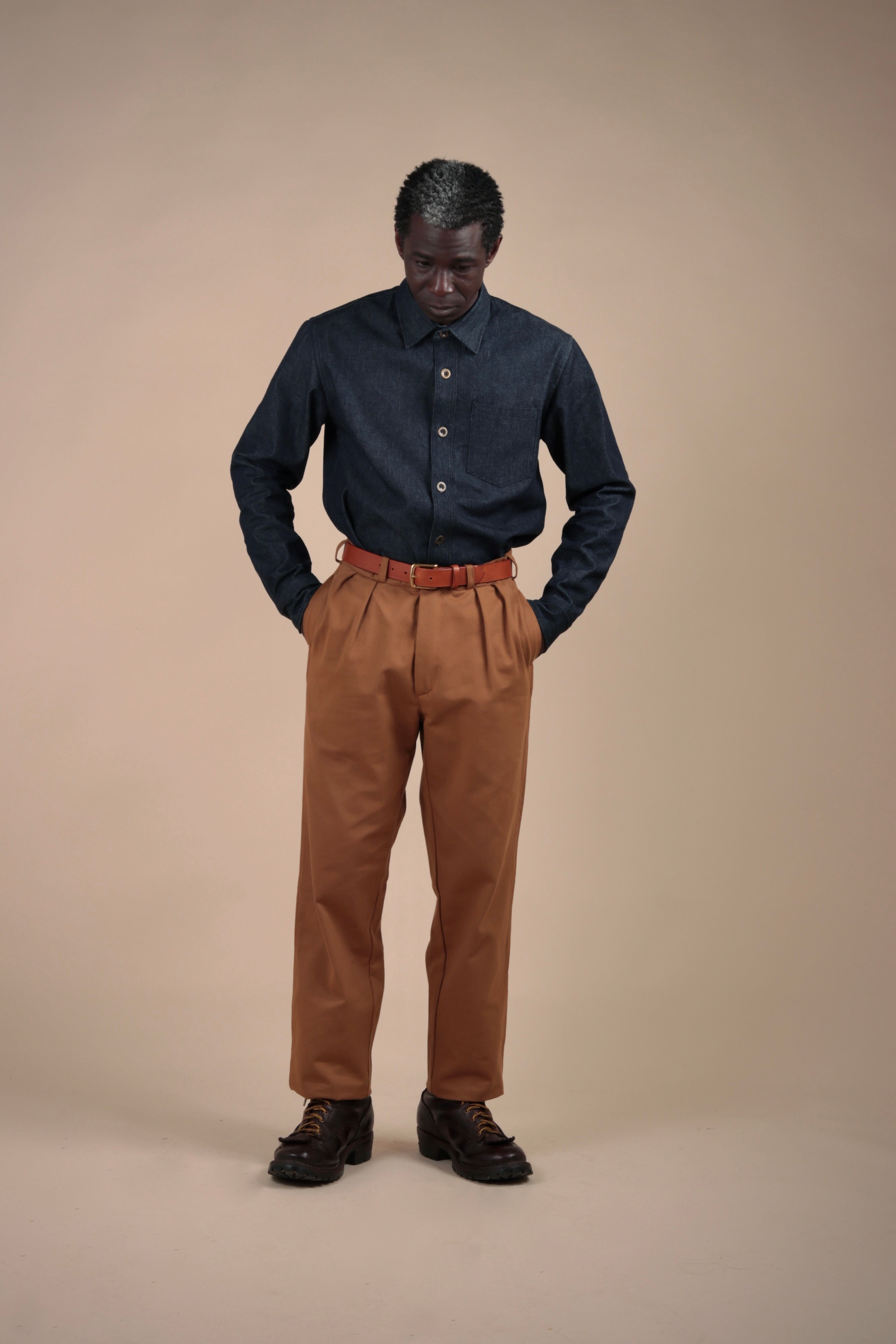 Man wears Carrier Company Classic Trouser in Tan with a Demin Collar Shirt
