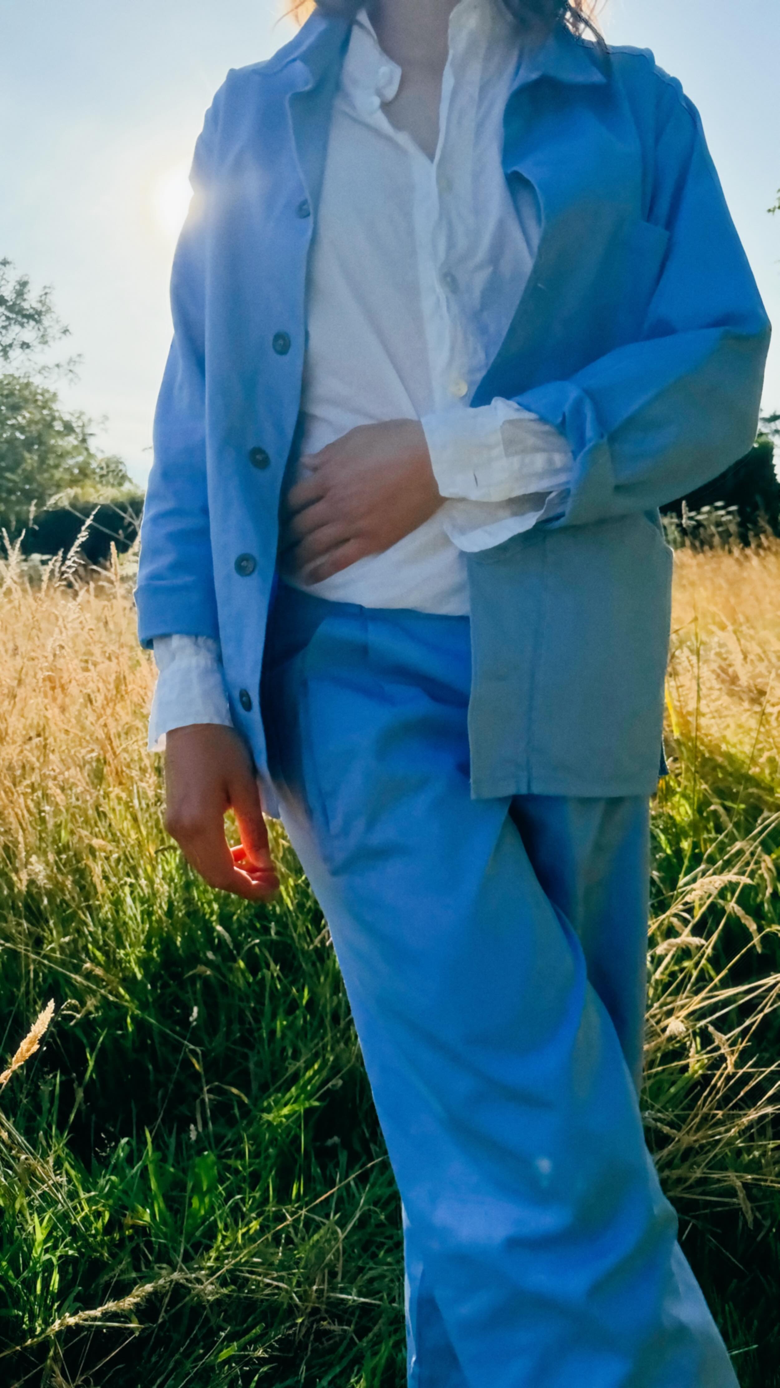 Minna wears Carrier Company Norfolk Work Jacket and Dutch Trousers in Powder Blue with Lightweight Collarless Work Shirt