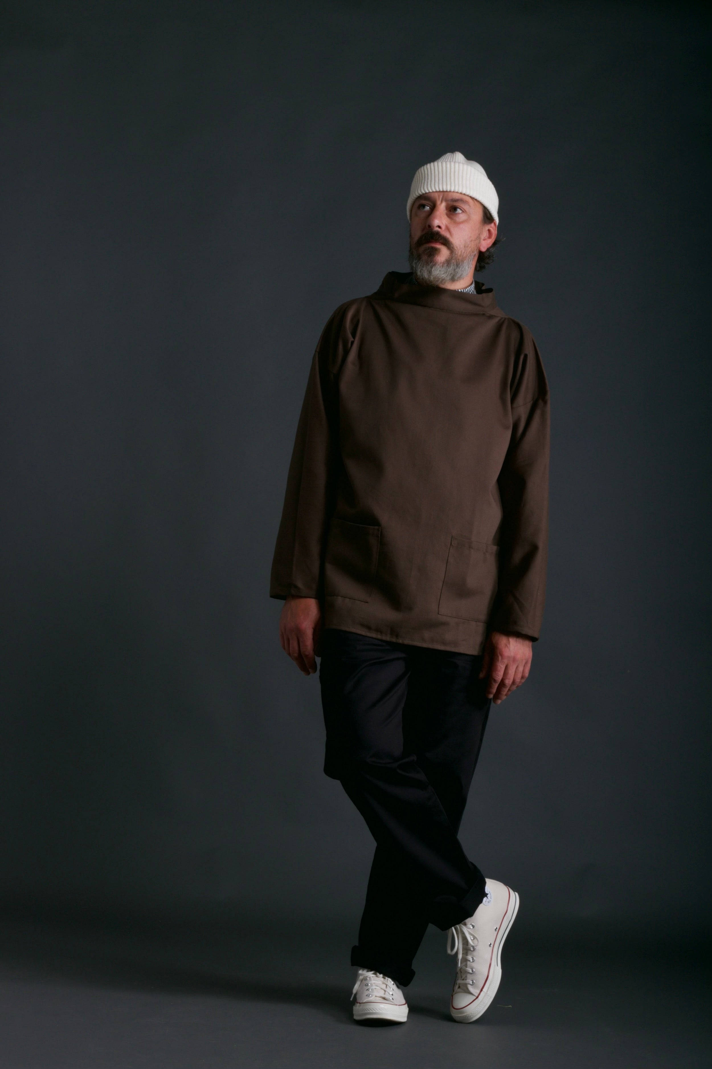 Man wears Traditional Norfolk Slop in Olive with Black Work Trousers and Ecru Wool Hat