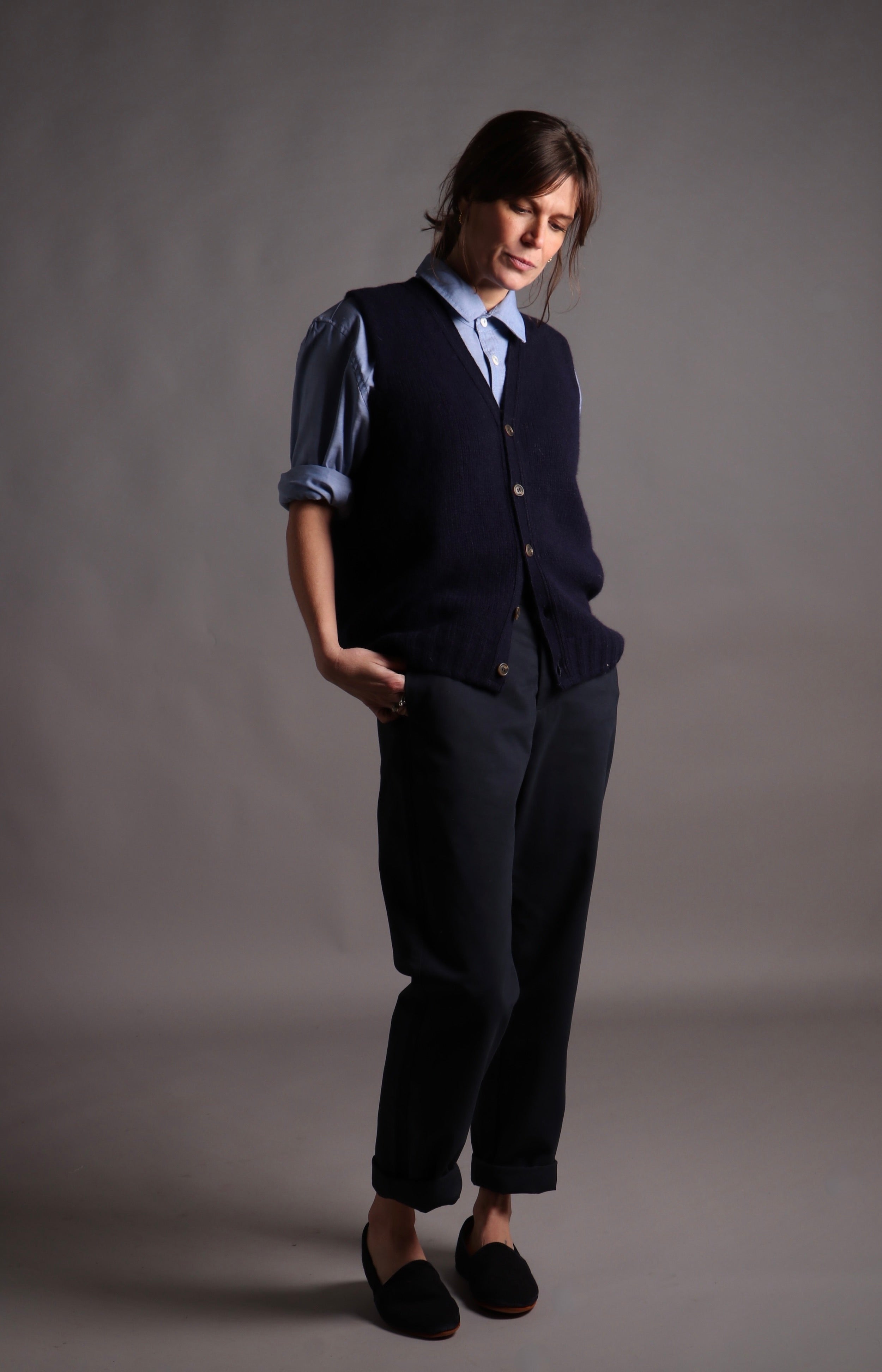 Kate wears Carrier Company Sleeveless Cardigan in Navy with Chambray Shirt and High Waist Trousers