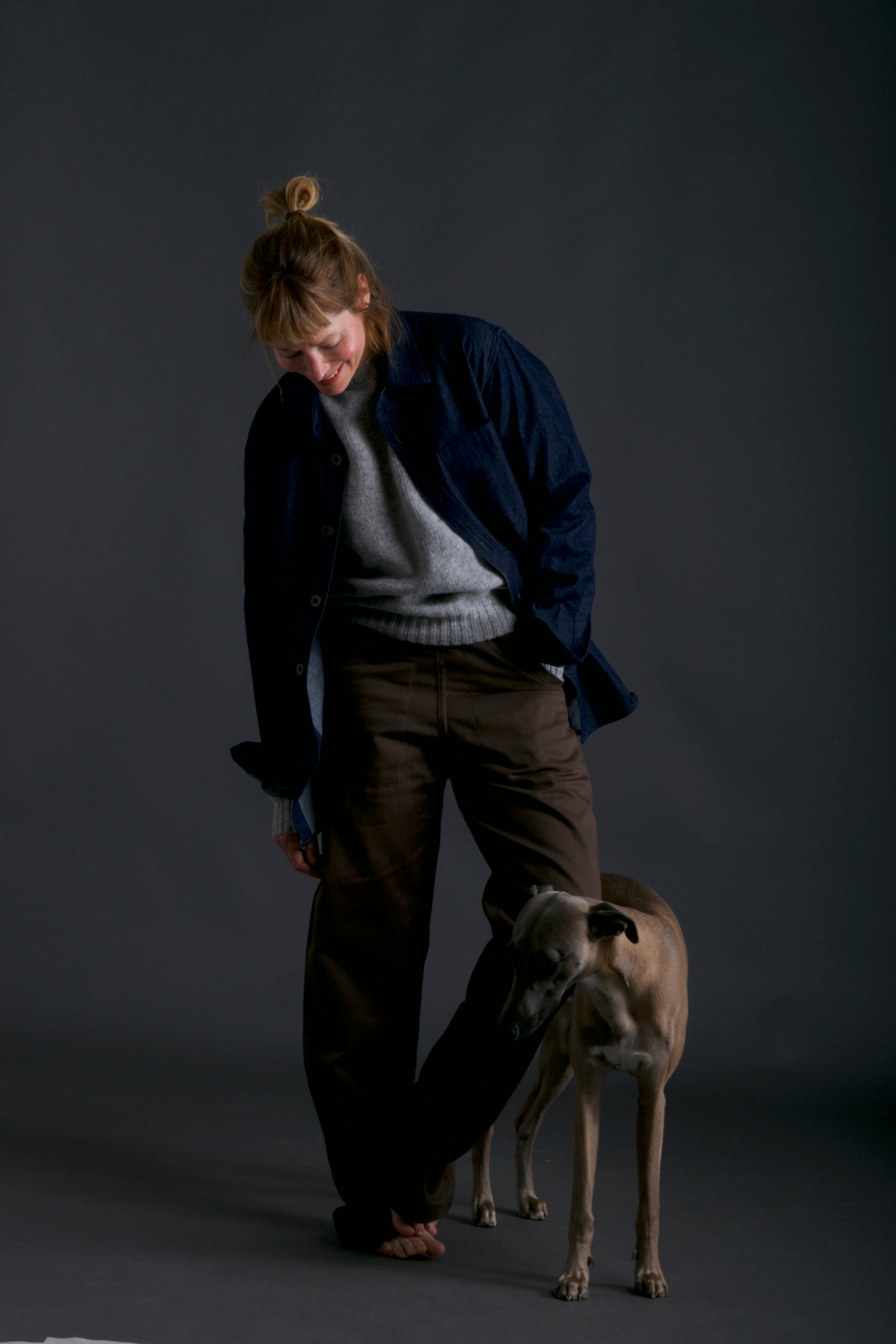 Woman wears Carrier Company Shetland Lambswool Jumper in Silver with Wool Collar Shirt and Olive Work Trouser