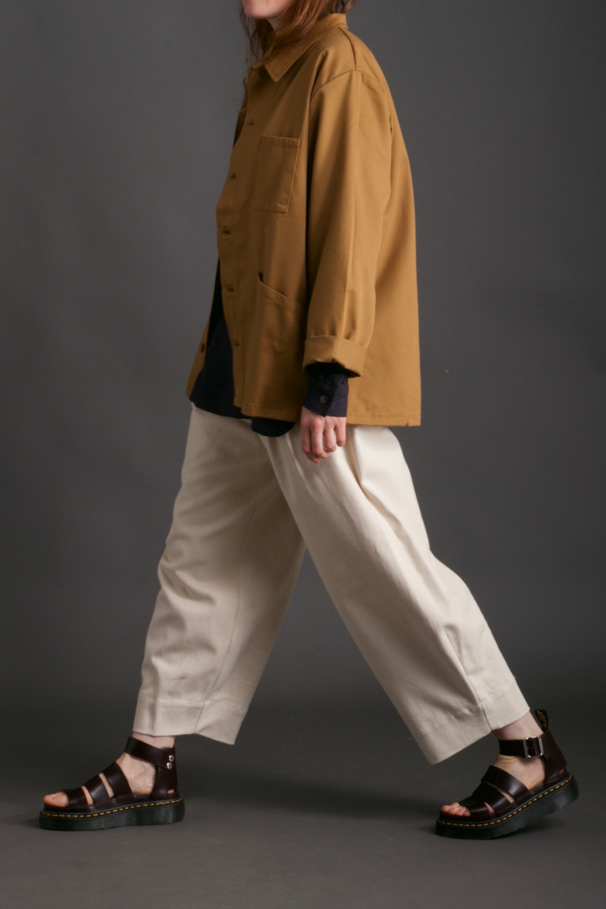 Woman wears Carrier Company Work Jacket in Tan with Dutch Trouser in Seeded Denim and Collarless Work Shirt in Navy Linen