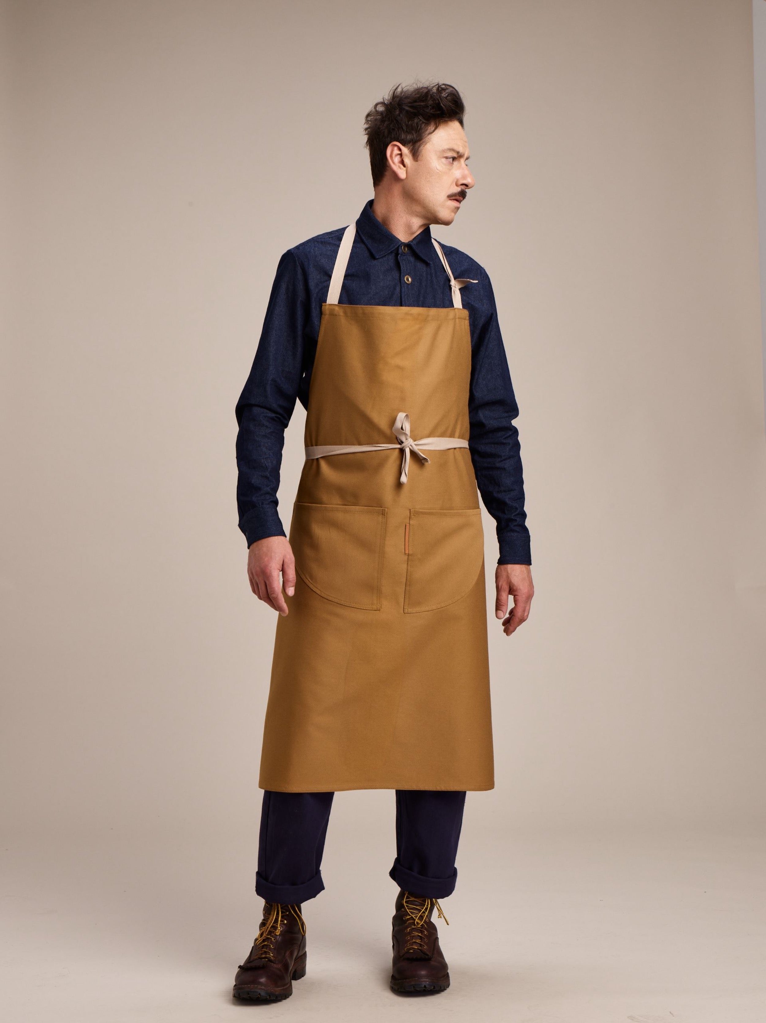 Man wears Carrier Company Long Apron in Tan