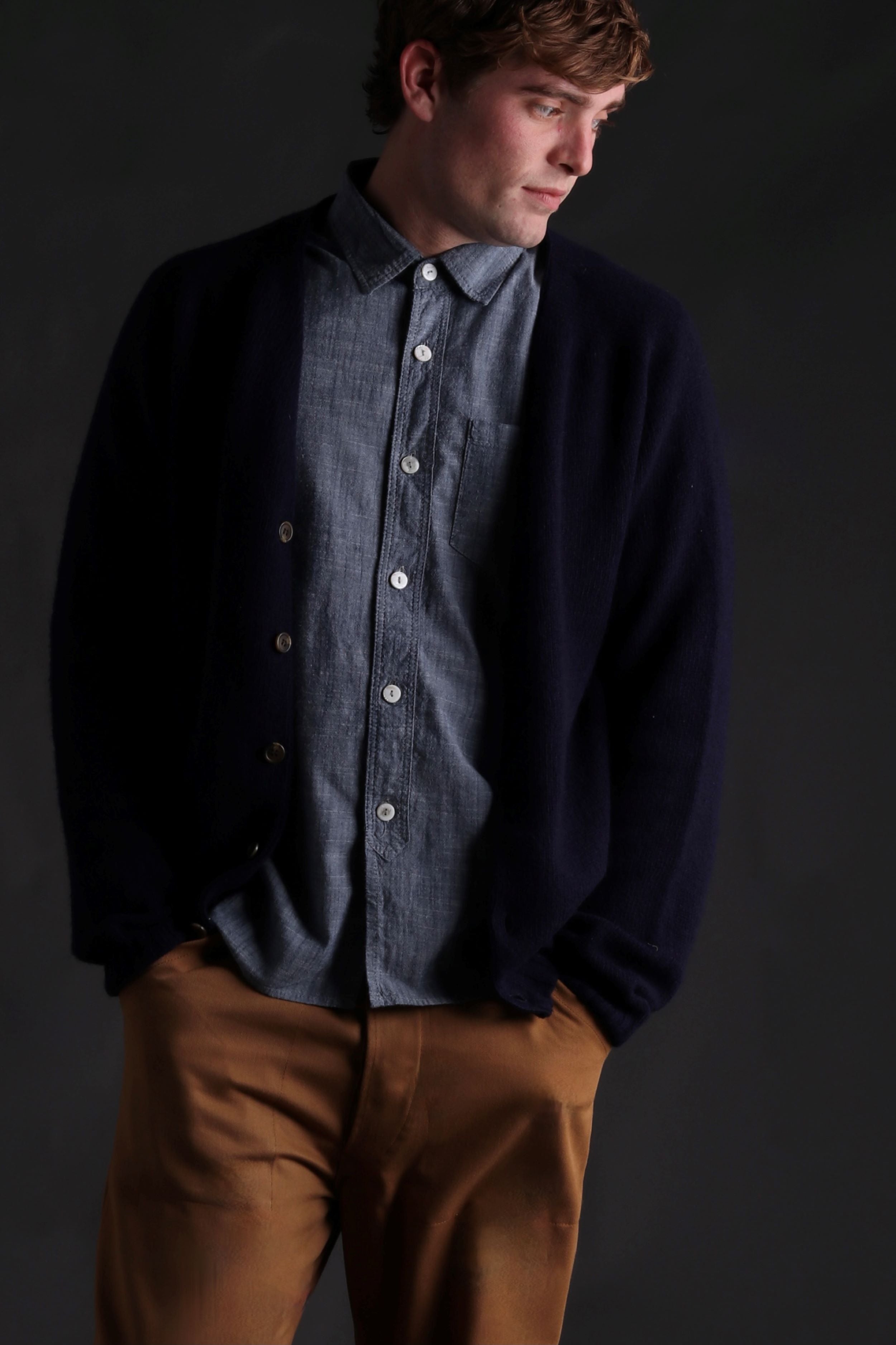 Man wearing Carrier Company Shetland Lambswool Cardigan in Navy with  Denim Shirt and Classic Work Trouser in Tan