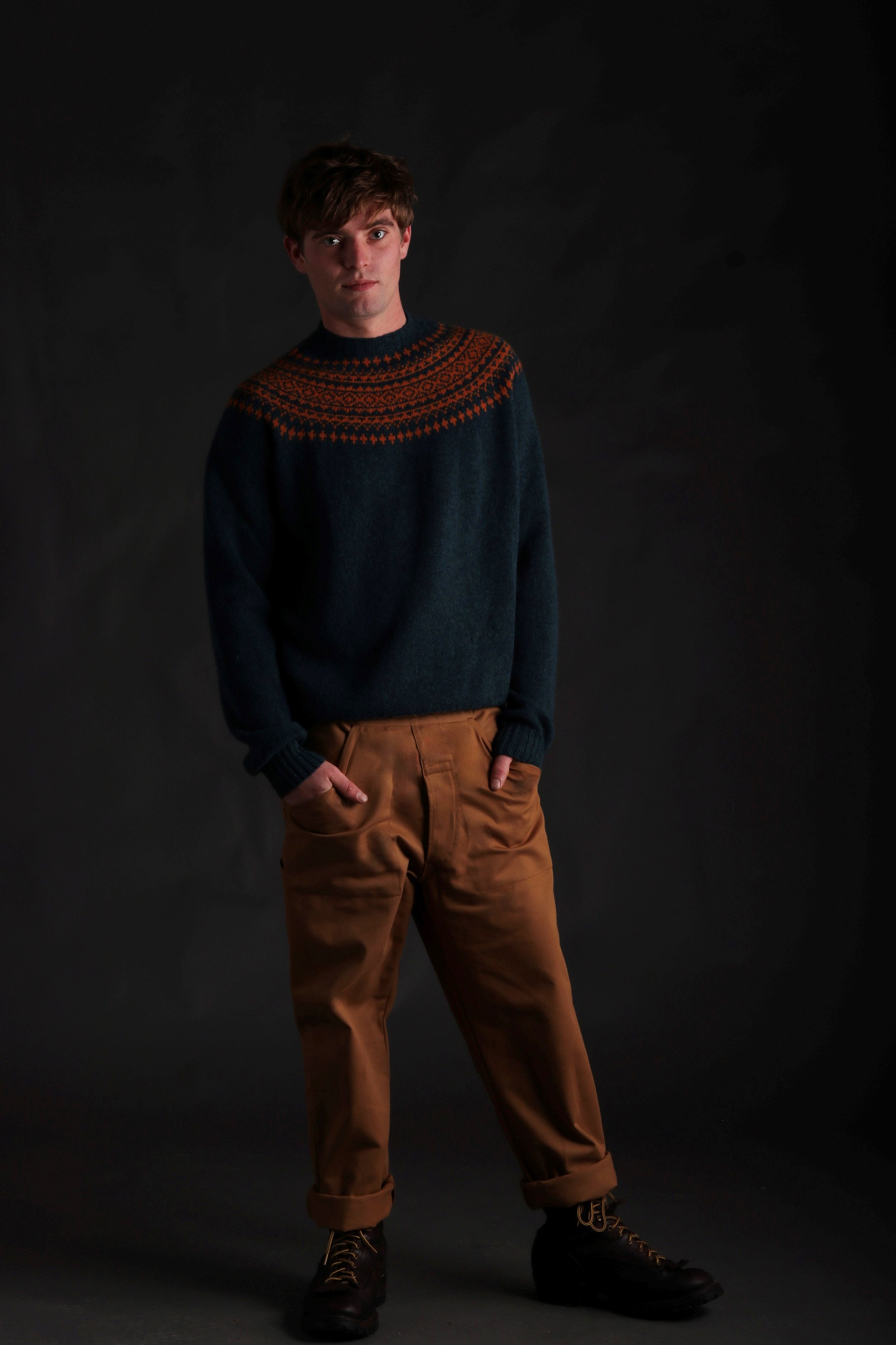 Man wears Carrier Company Shetland Yoke Jumper in ginger and Teal