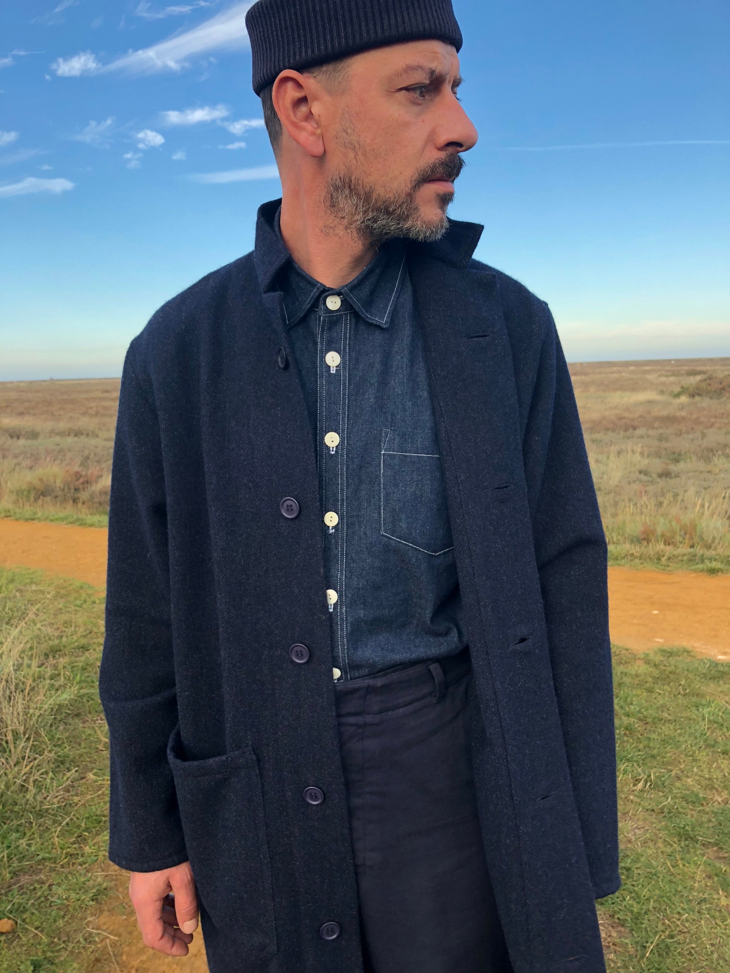 Man wearing Carrier Company Men's Work Trouser in Navy with Denim Collar Shirt, Navy Wool Coat and Merino Hat