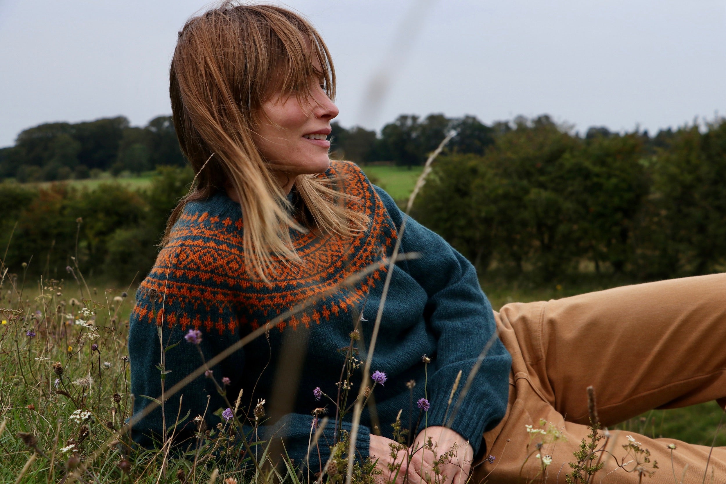Woman wearing Carrier Company Shetland Lambswool Yoke Jumper in Ginger and Teal with tan Women's Work Trouser