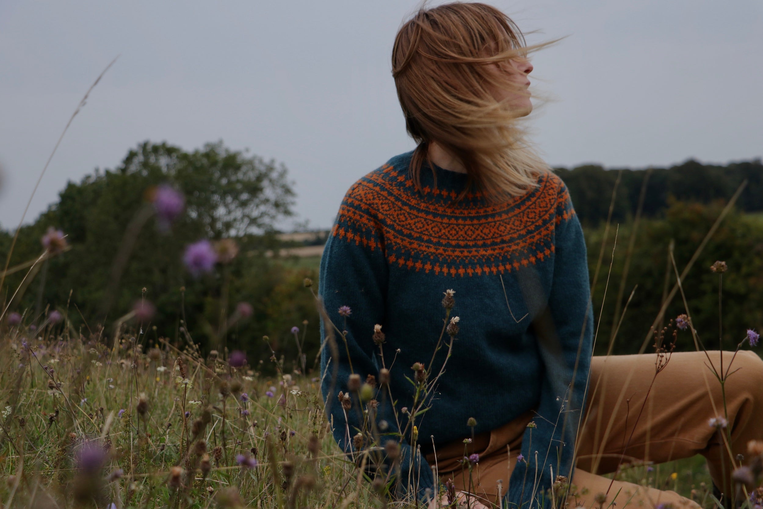 Woman wearing Carrier Company Shetland Lambswool Yoke Jumper in Ginger and Teal with tan Women's Work Trouser