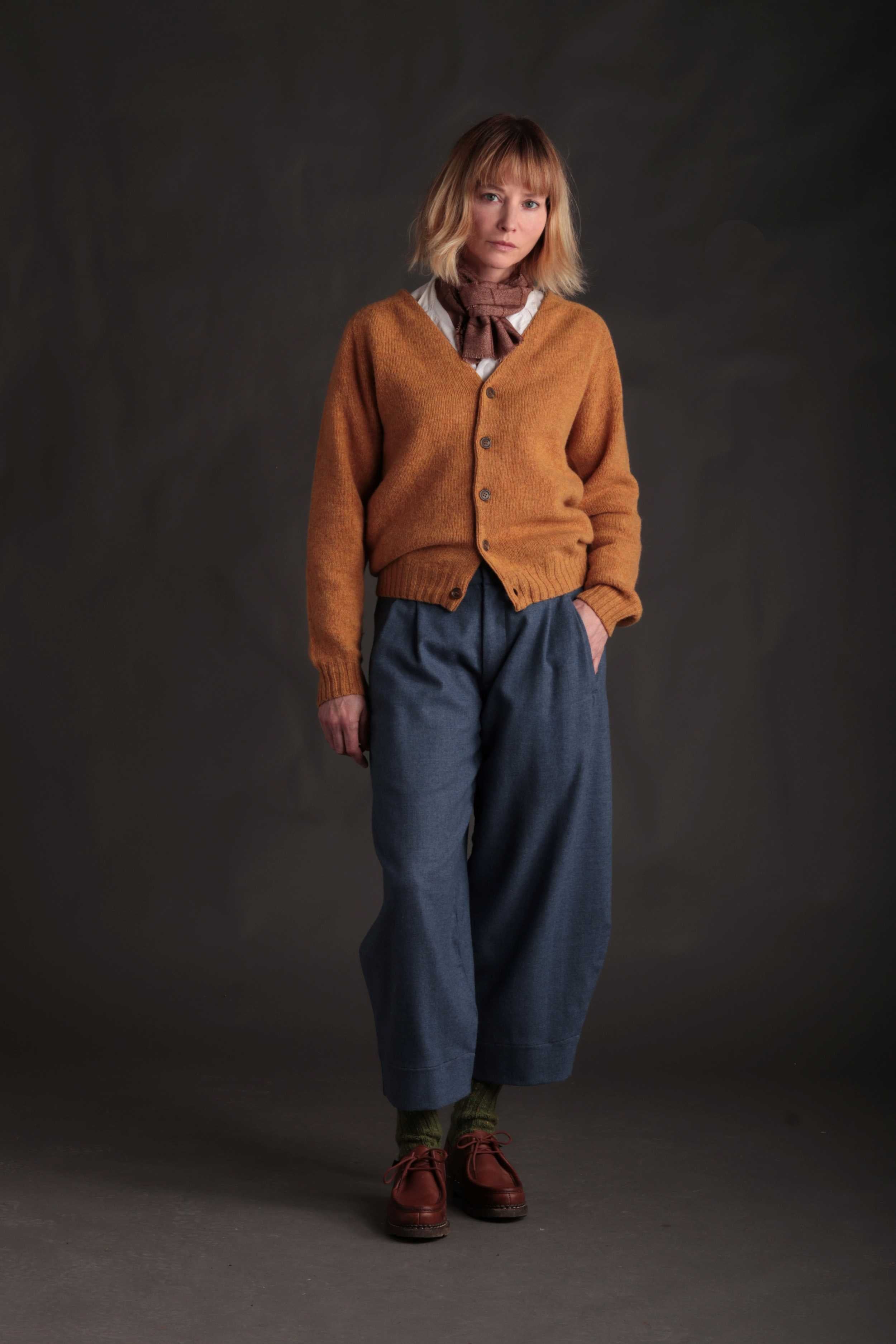 Woman wears Carrier Company Cardigan in Cumin with Dutch Trousers in Wool