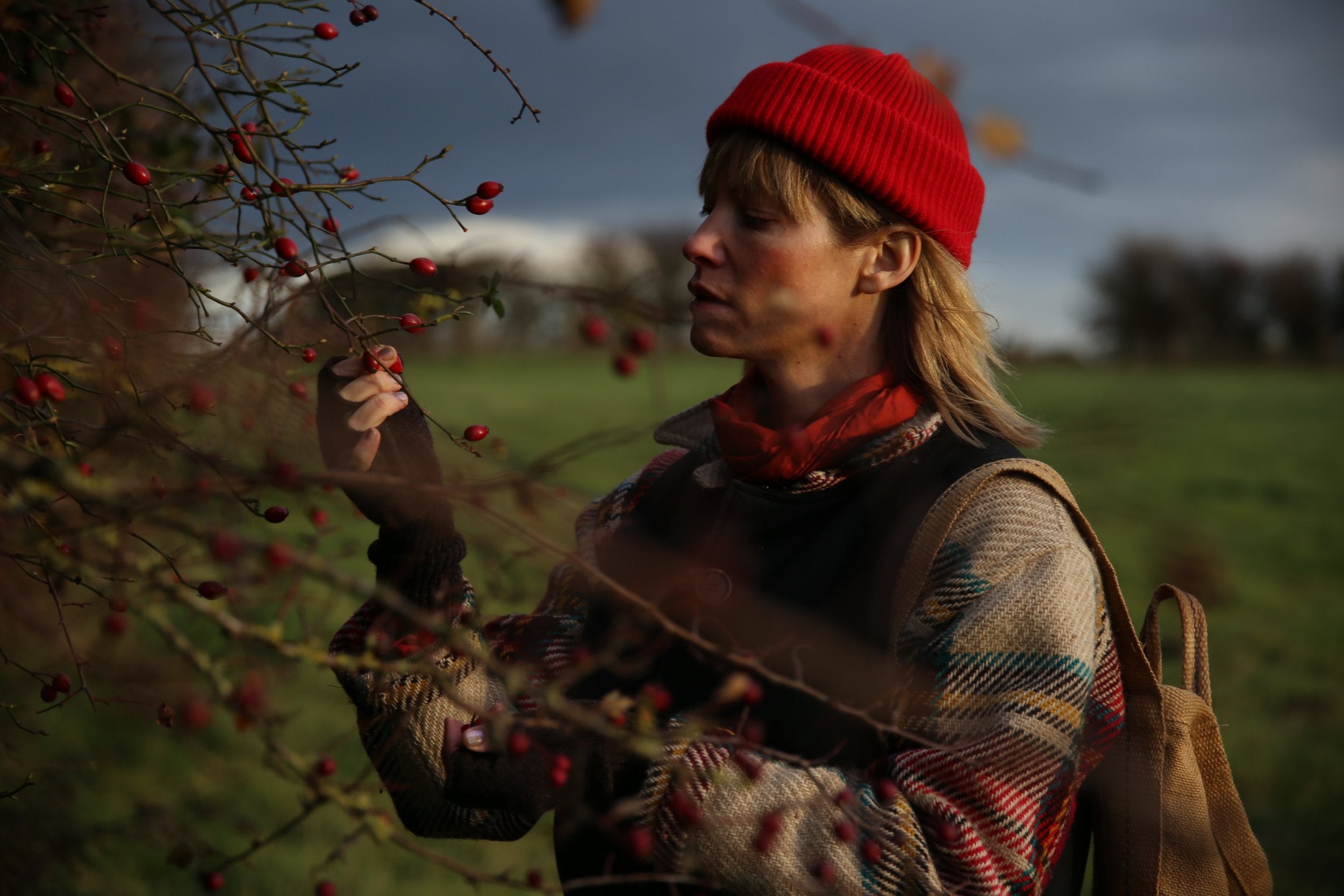 Woman wears Carrier Company Wool Hat in Poppy Red with Celtic Wool Jacket and Gathering Glove  Edit alt text