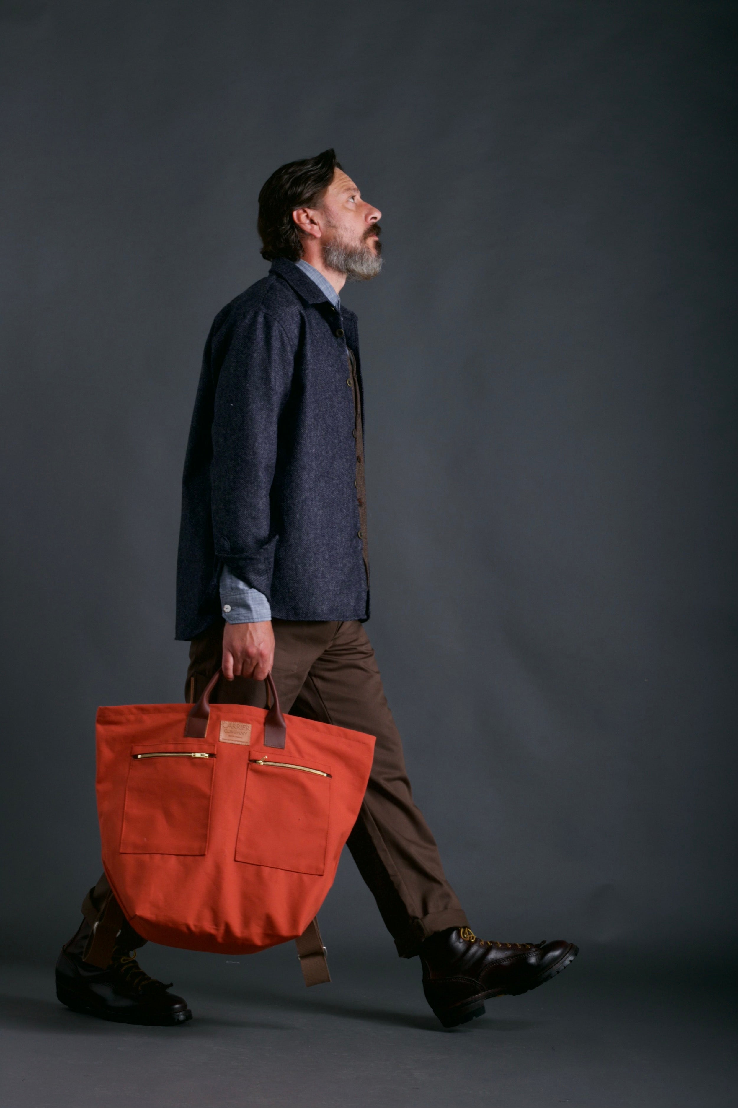 Man carries Carrier Company Backpack in Orange