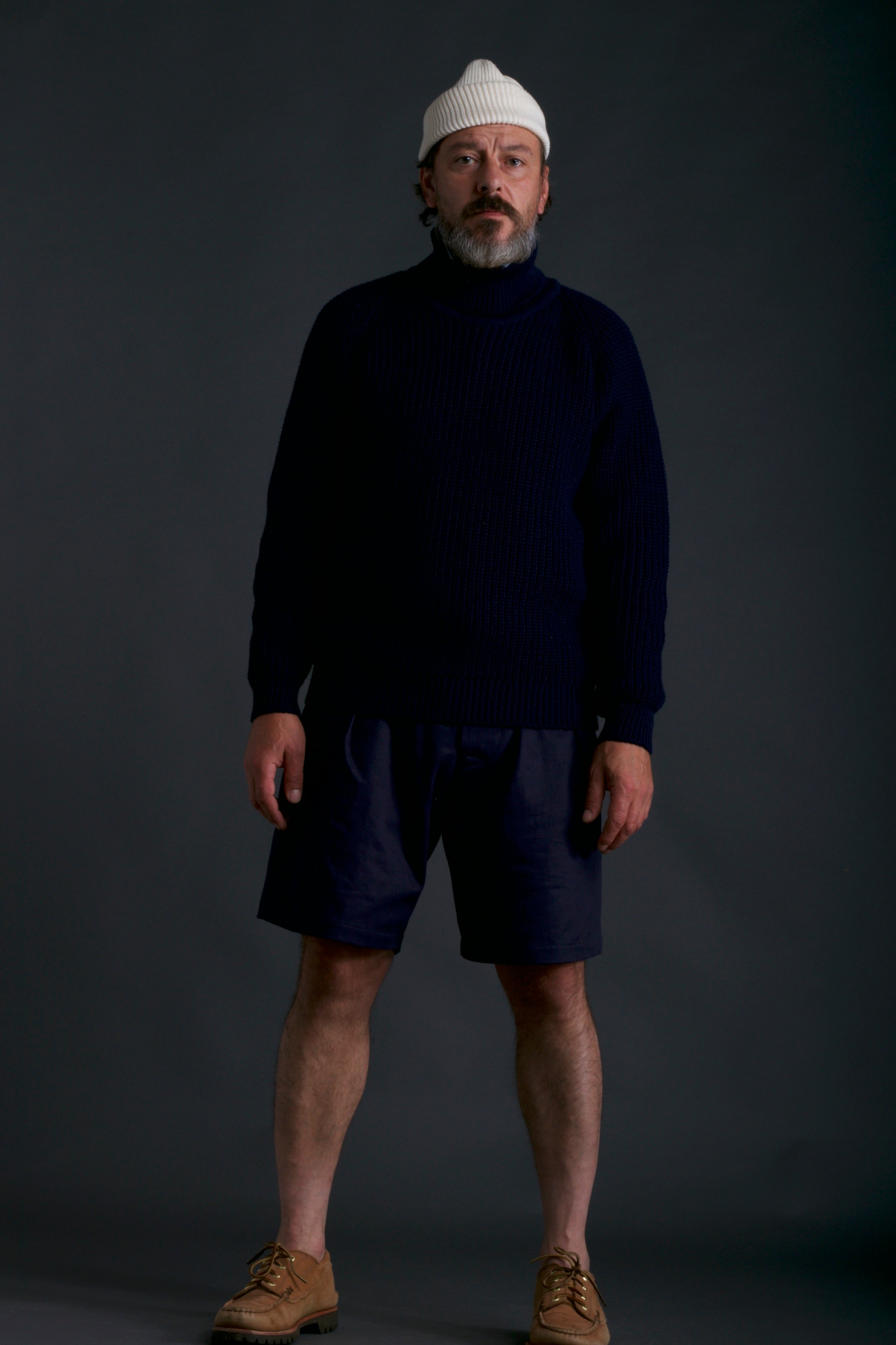 Man wears Carrier Company Grandpa Shorts in Navy with Fisherman's Jumper and Wool Hat