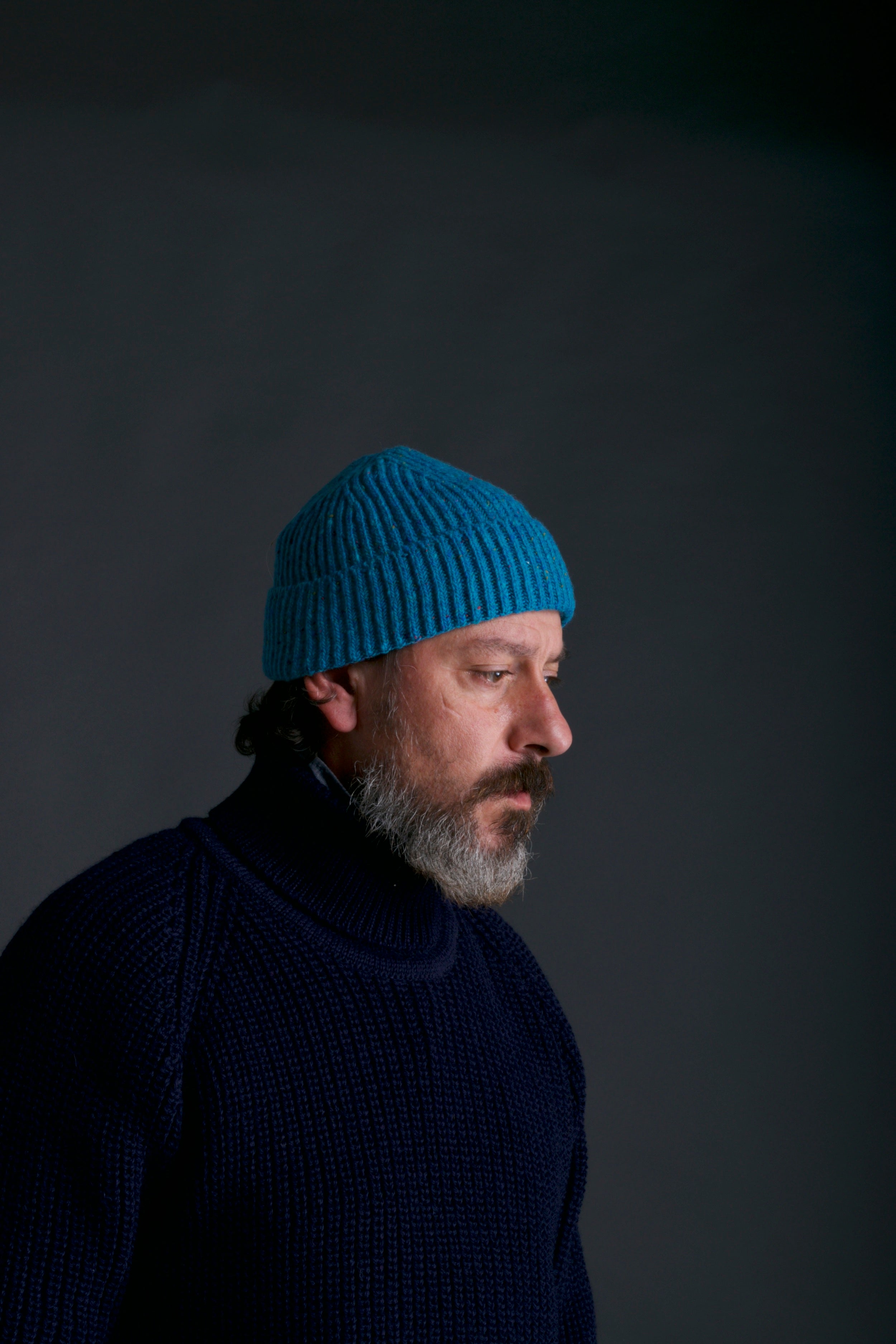 Man wears Carrier Company Donegal Wool Hat  in Turquoise with Navy Fisherman's Jumper
