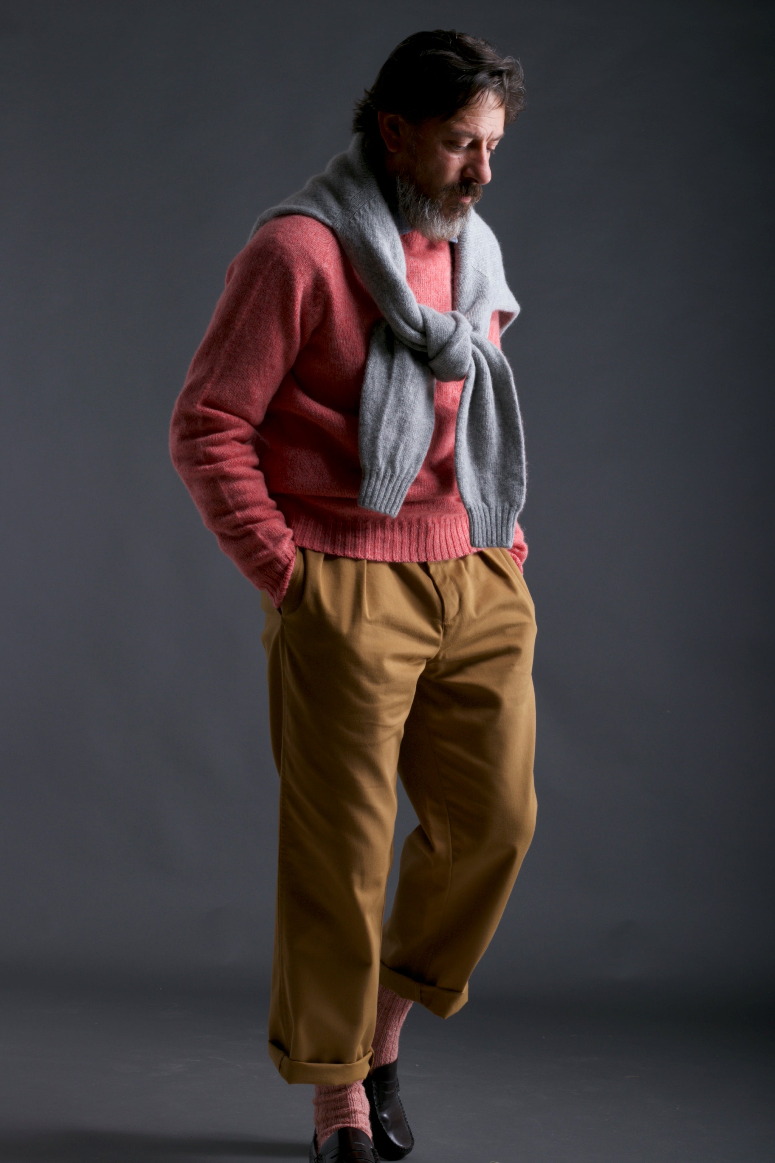 Man wears Carrier Company Classic Trouser in Tan, Shetland Lambswool Jumper in Salmon with Matching Wool Socks