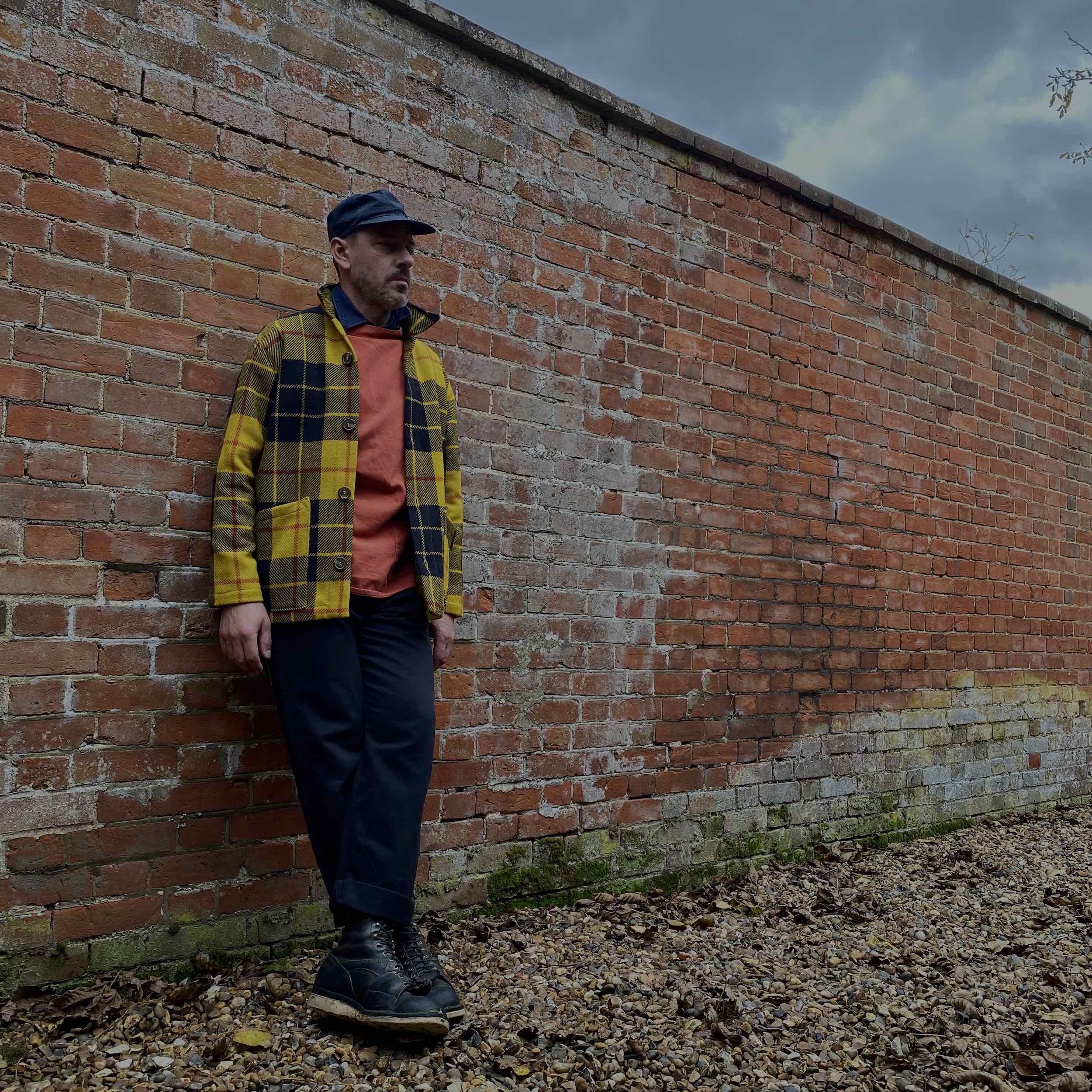 Man wearing Celtic Wool Jacket in Black and Yellow Check with Traditional Slop and black Men's Dungarees