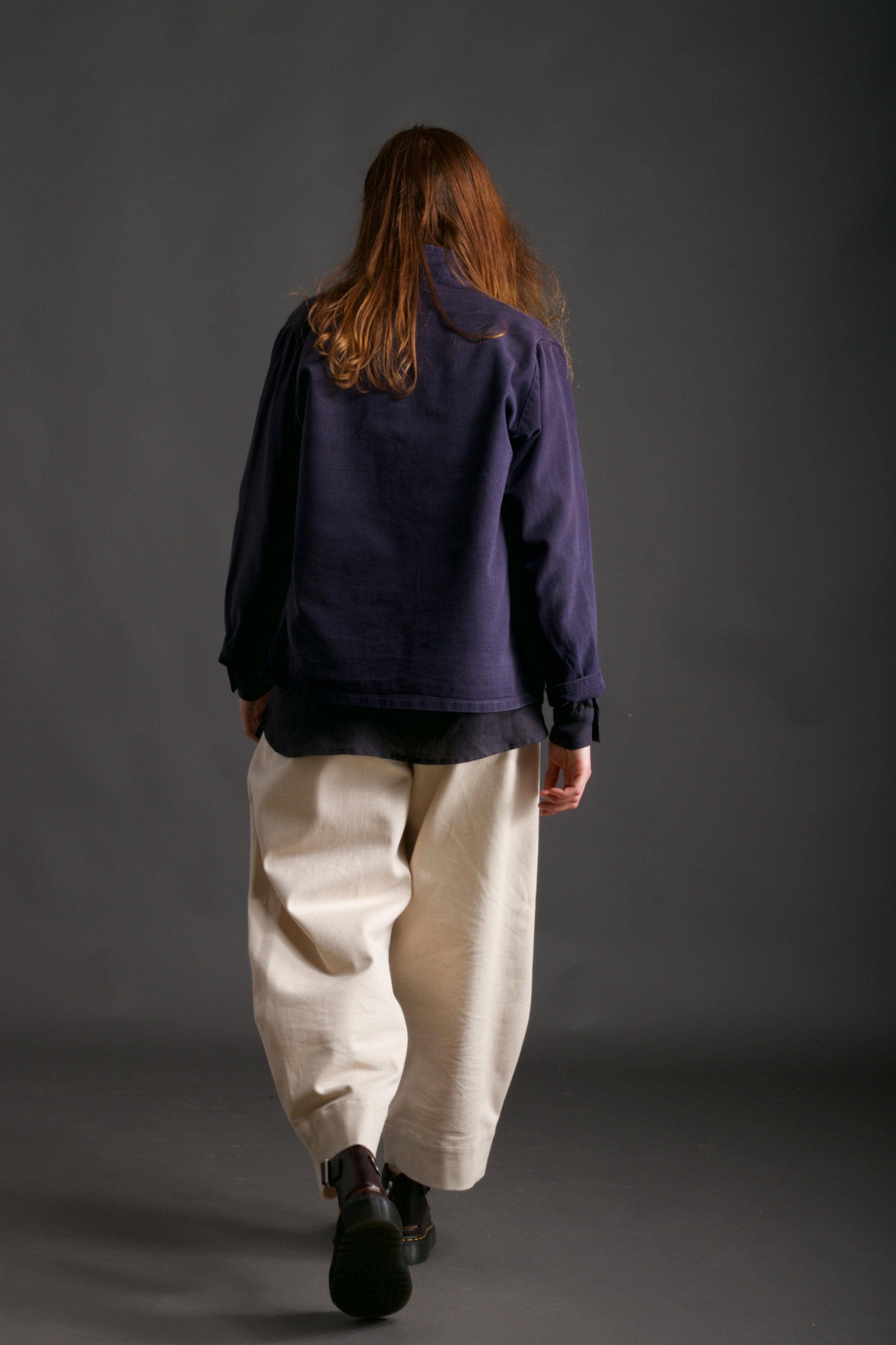 Woman wearing Carrier Company Traditional Norfolk Work Jacket in Navy with Dutch Trouser in Seeded Denim and Collarless Work Shirt in Navy Linen