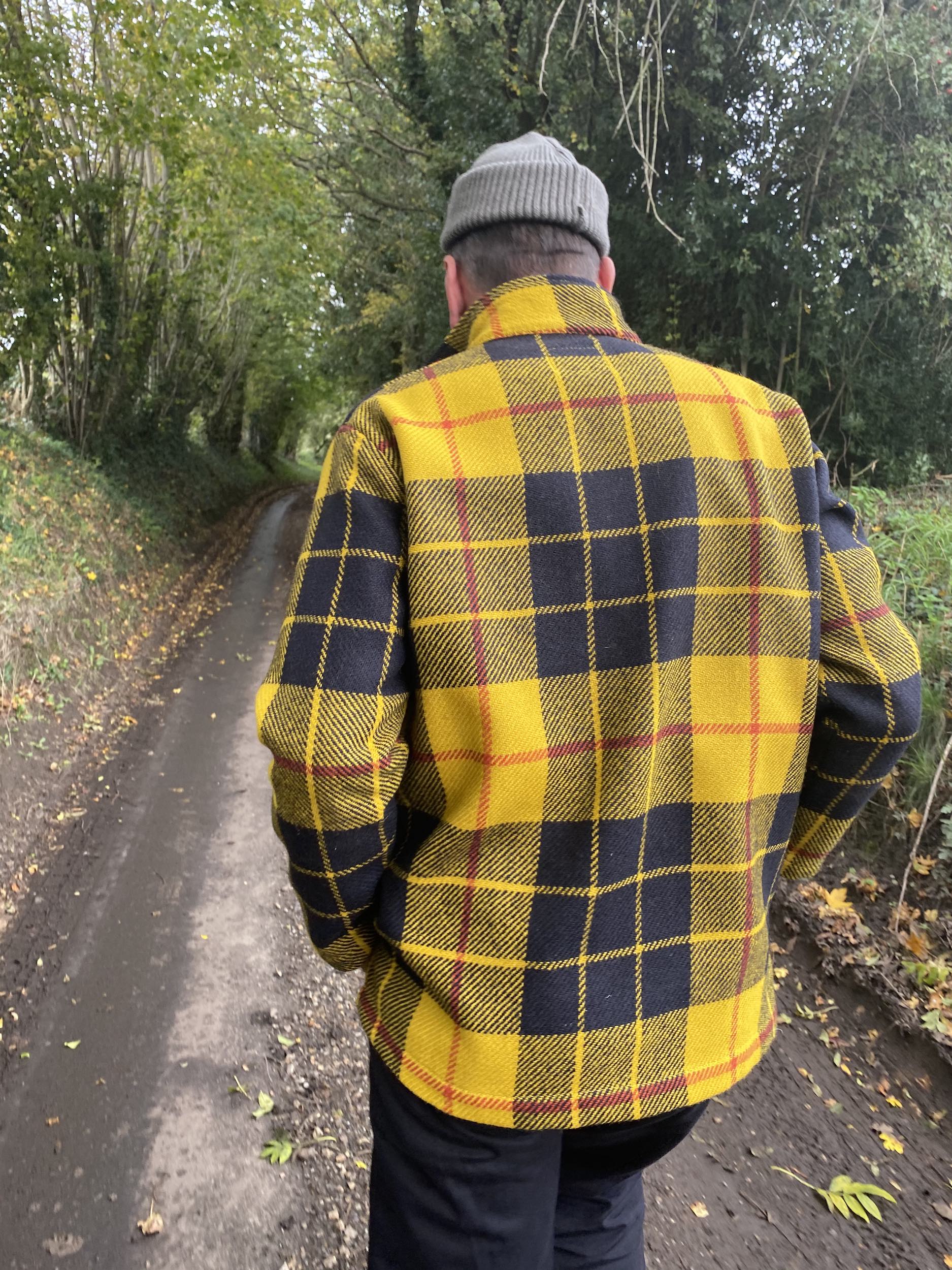 Man wearing Celtic Wool Jacket in Black and Yellow Check with wool hat and black Men's Dungarees