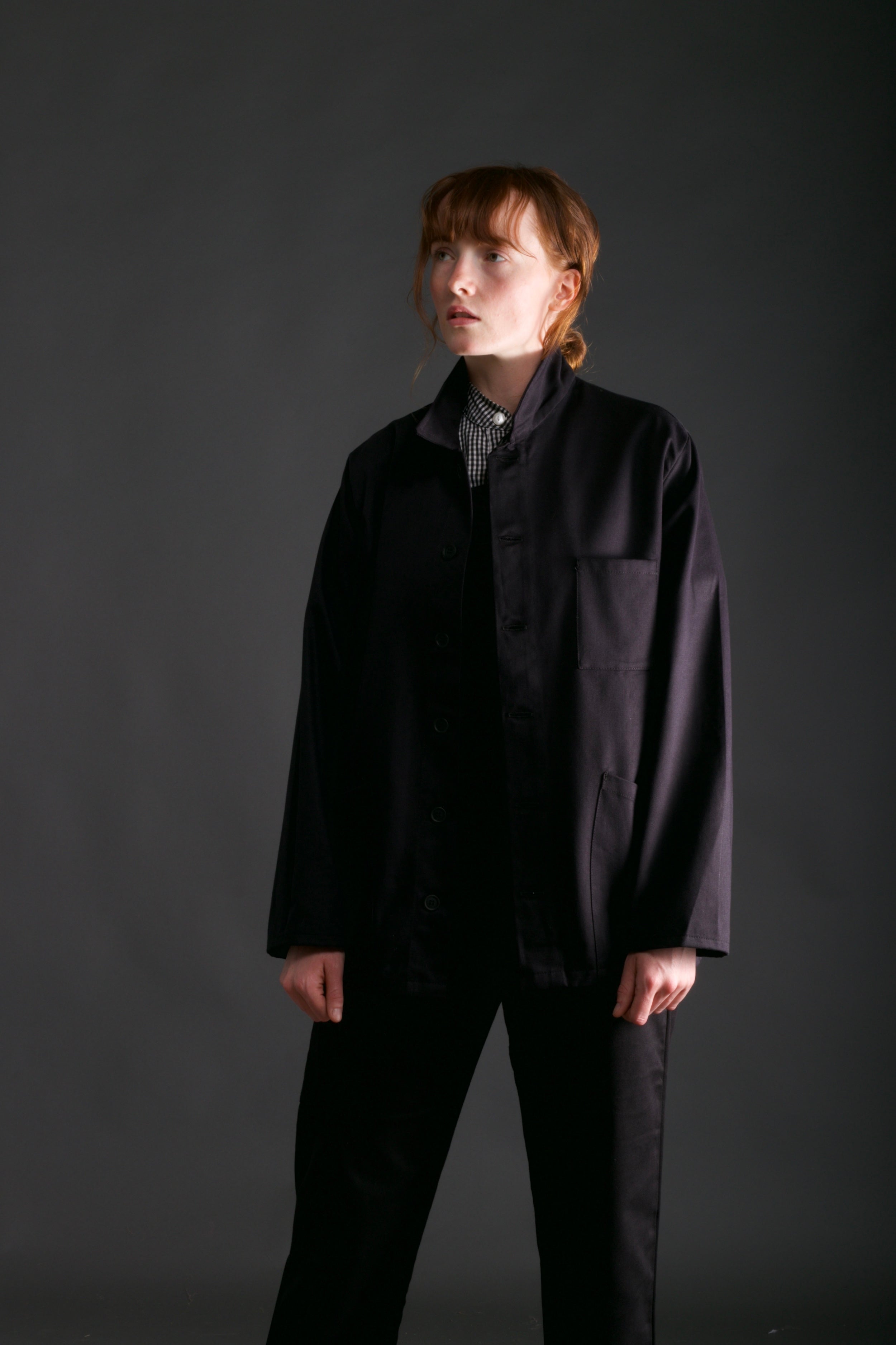 Woman wears Carrier Company Norfolk Work jacket in Black with Women's Dungarees and Organic Cotton Collarless Shirt in Black Gingham