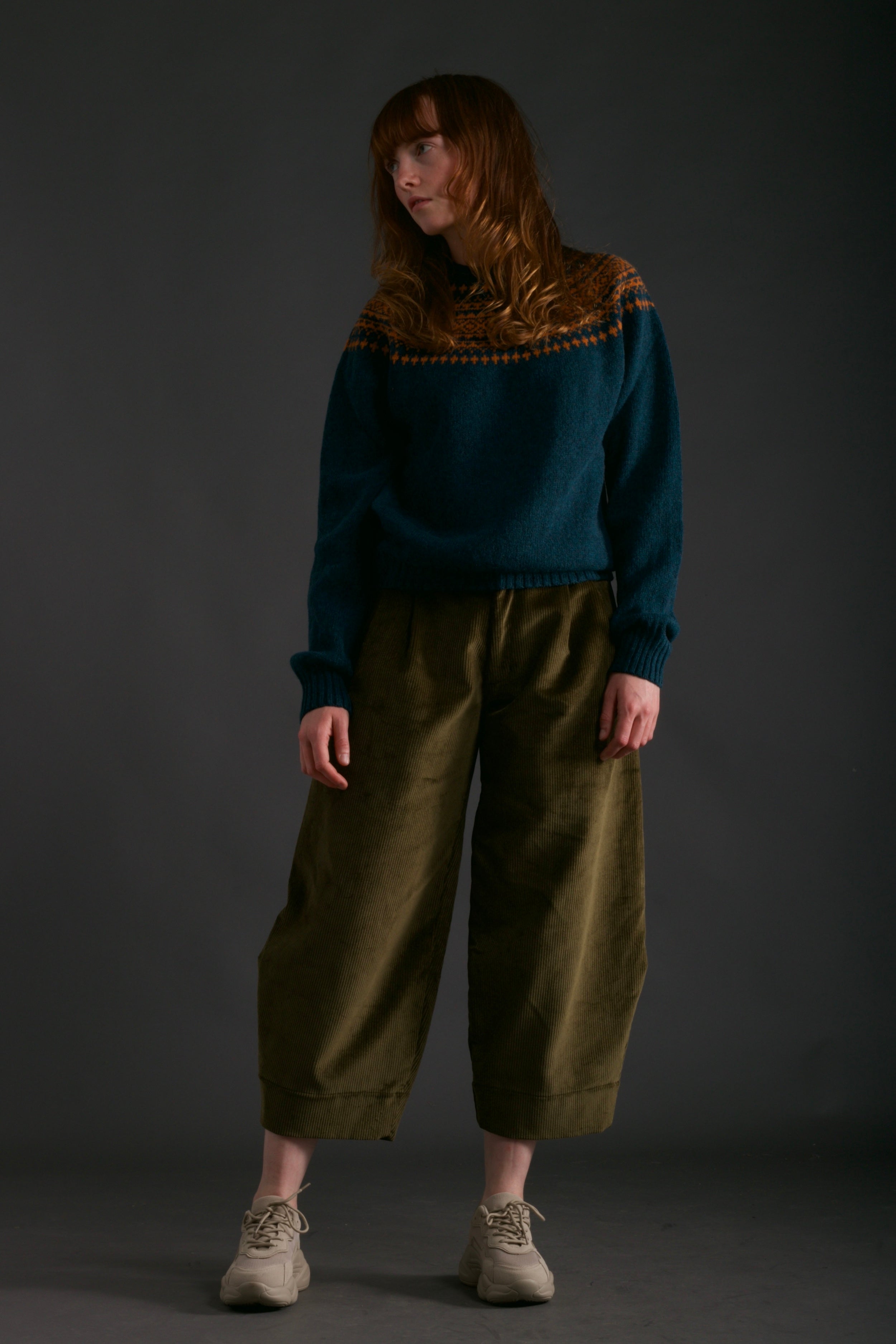Woman wears Carrier Company Shetland Yoke Jumper in ginger and Teal with Dutch Trouser in Corduroy