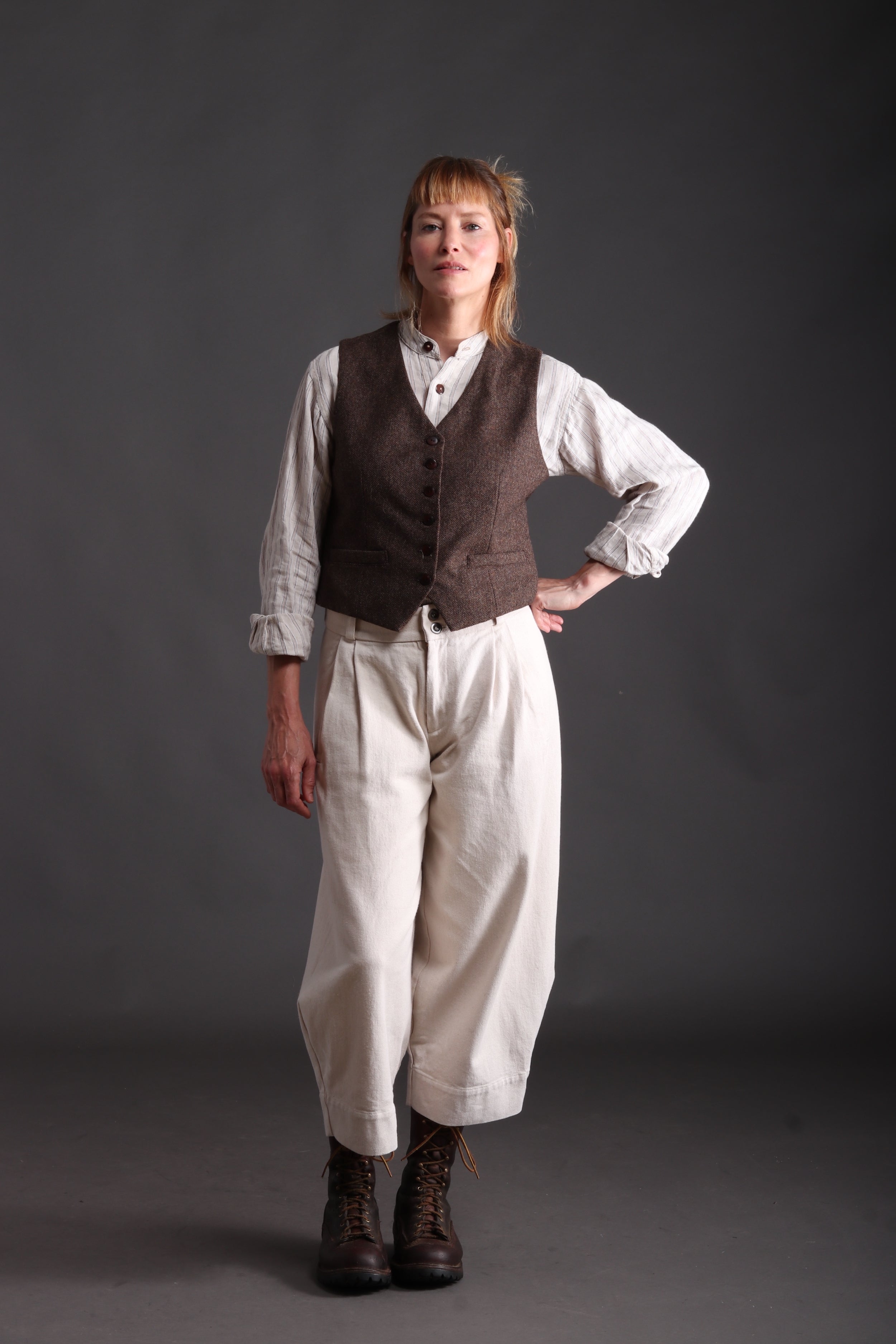 Woman wears Carrier Company Women's Wool Waistcoat in brown with Linen Collarless Worksheet and Dutch trouser in Seeded Denim