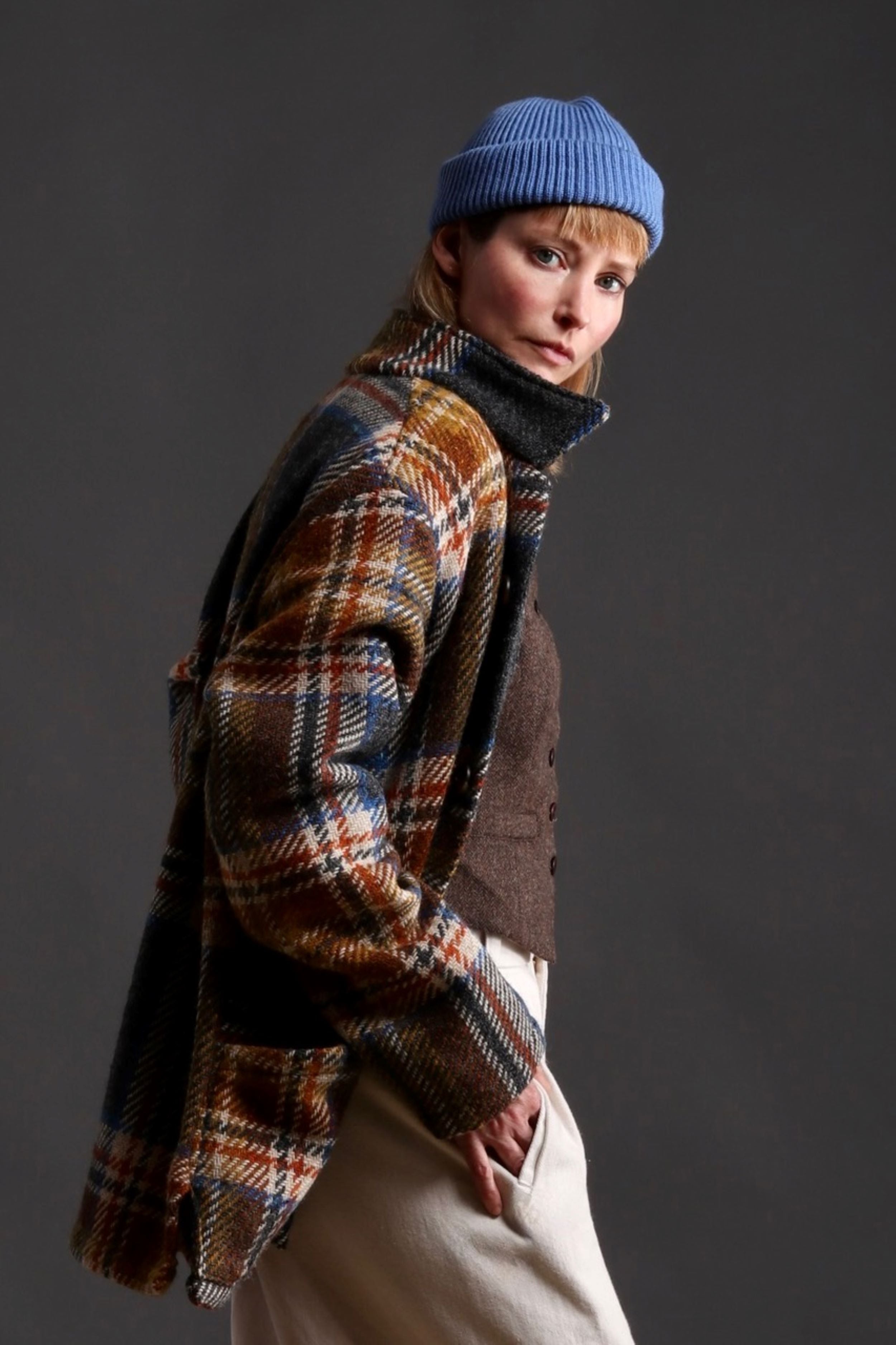 Woman wears Celtic Wool Jacket in Slate with Seeded Denim Dutch Trouser, Womens Waistcoat in Brown Wool, Collarless Work Shirt in Striped Linen and Merino Wool Hat in Sky Blue