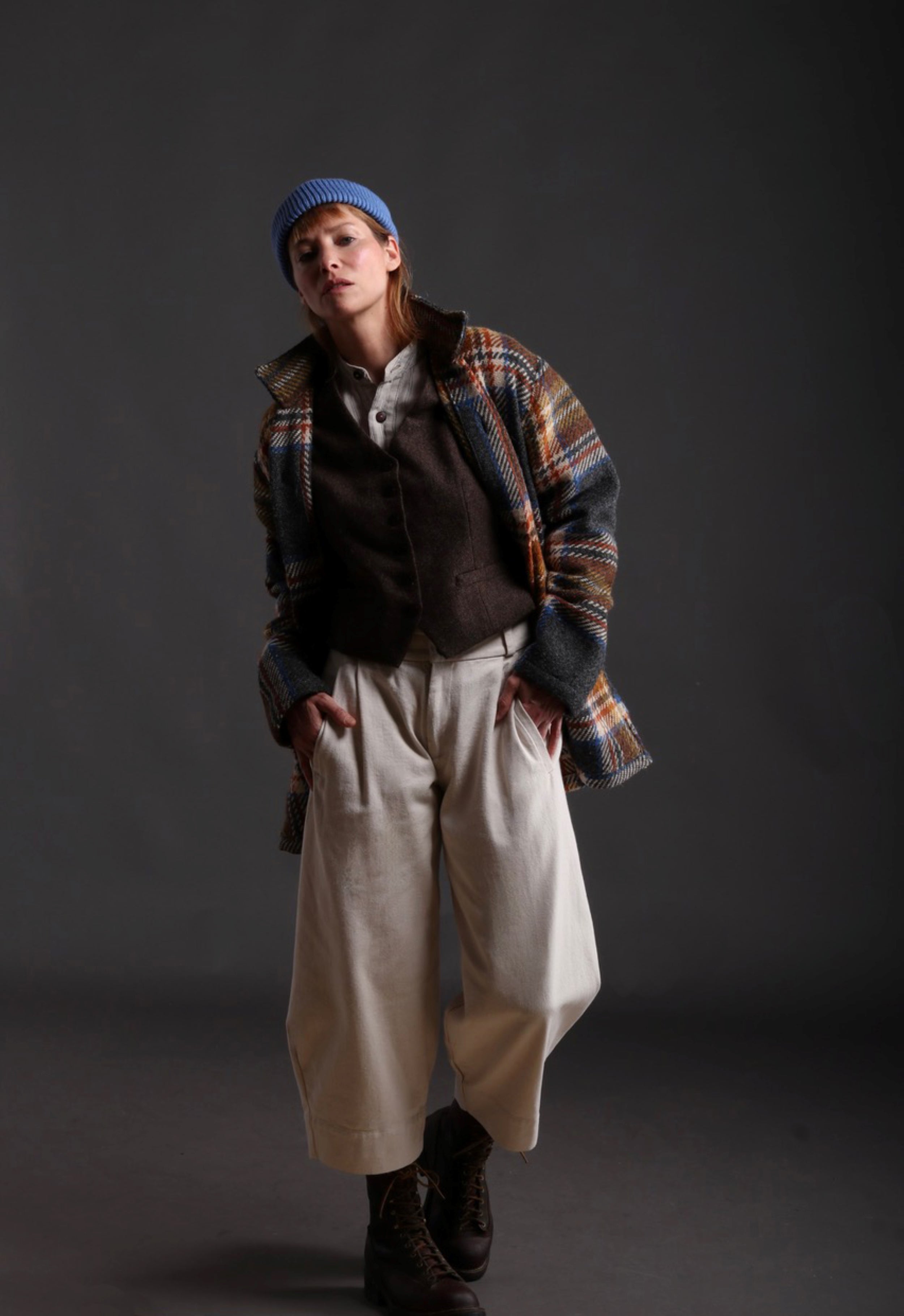 Woman wears Celtic Wool Jacket in Slate with Seeded Denim Dutch Trouser, Womens Waistcoat in Brown Wool, Collarless Work Shirt in Striped Linen and Merino Wool Hat in Sky Blue