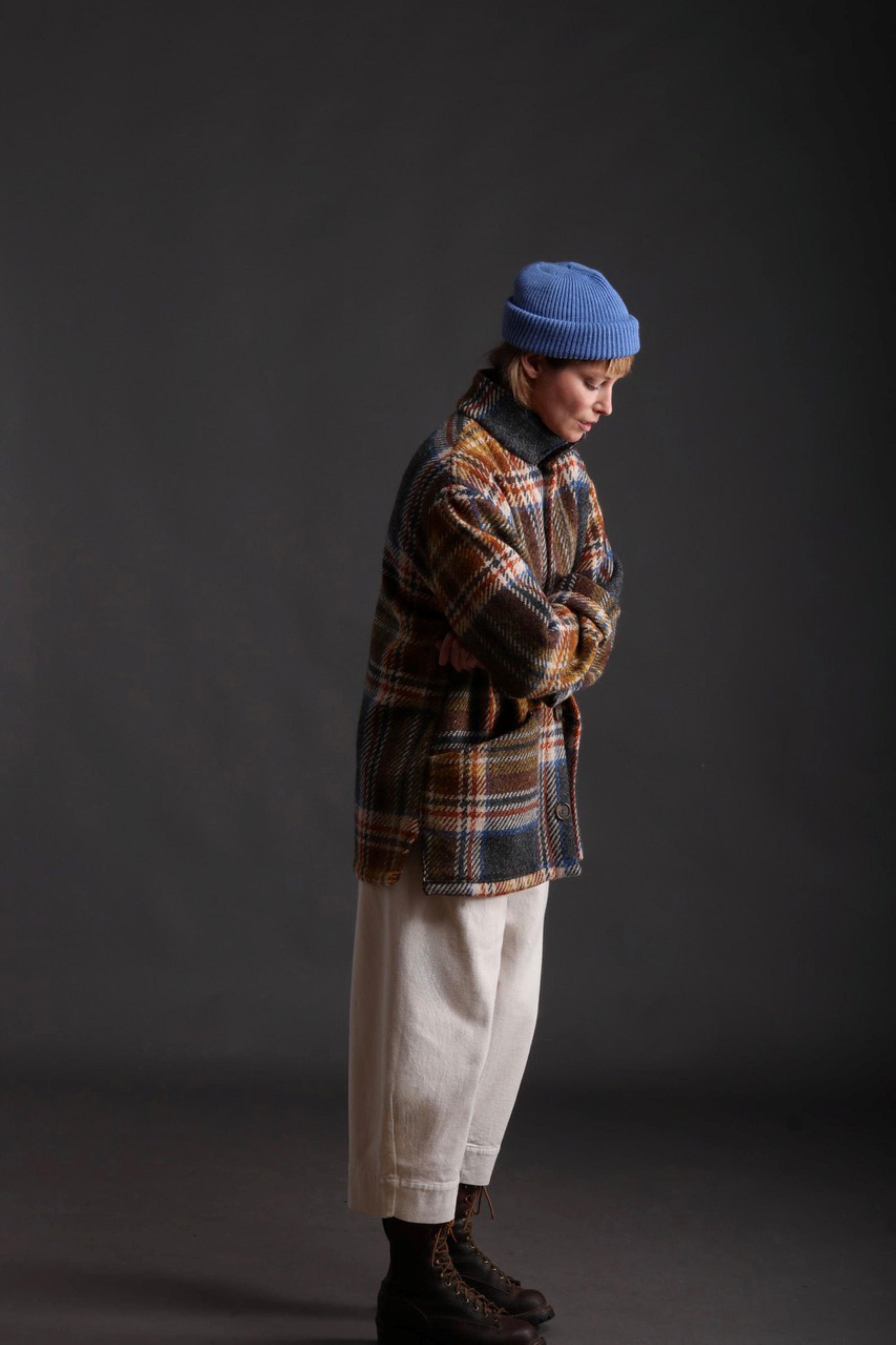 Woman wears Celtic Wool Jacket in Slate with Seeded Denim Dutch Trouser, Womens Waistcoat in Brown Wool, Collarless Work Shirt in Striped Linen and Merino Wool Hat in Sky Blue