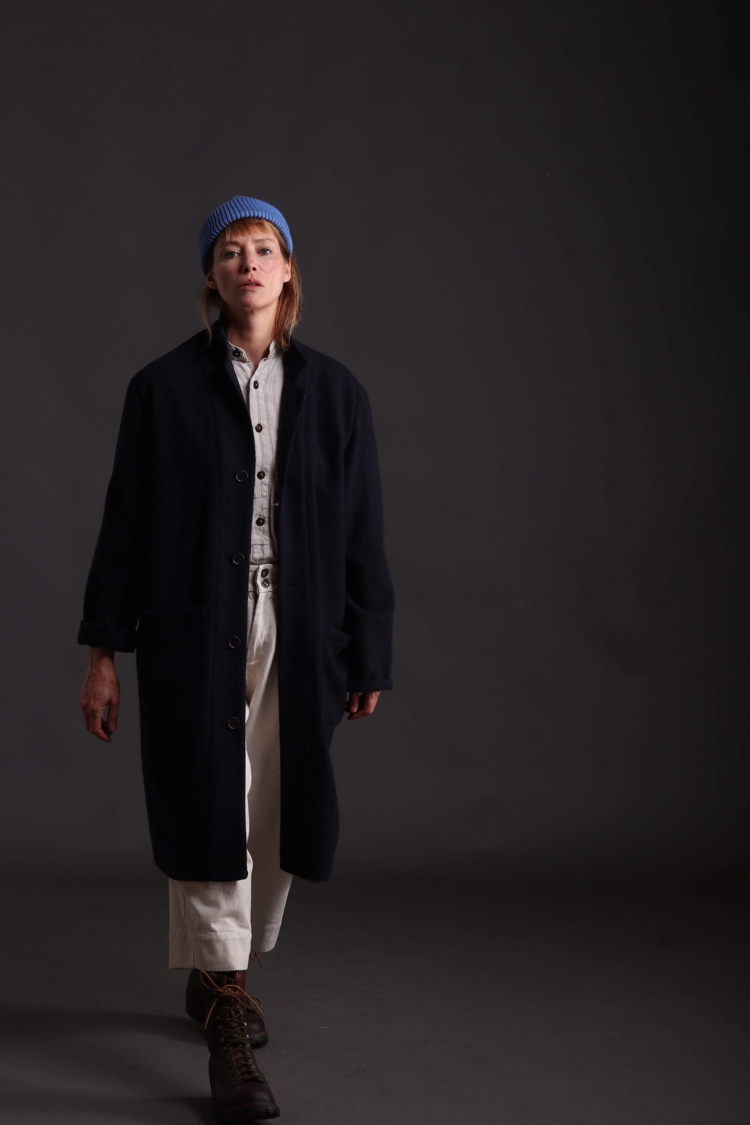 Sienna wears Carrier company Wool Coat in Navy with Collarless Work Shirt in Striped Linen, Dutch Trouser in Seeded Denim and Wool Hat in Sky