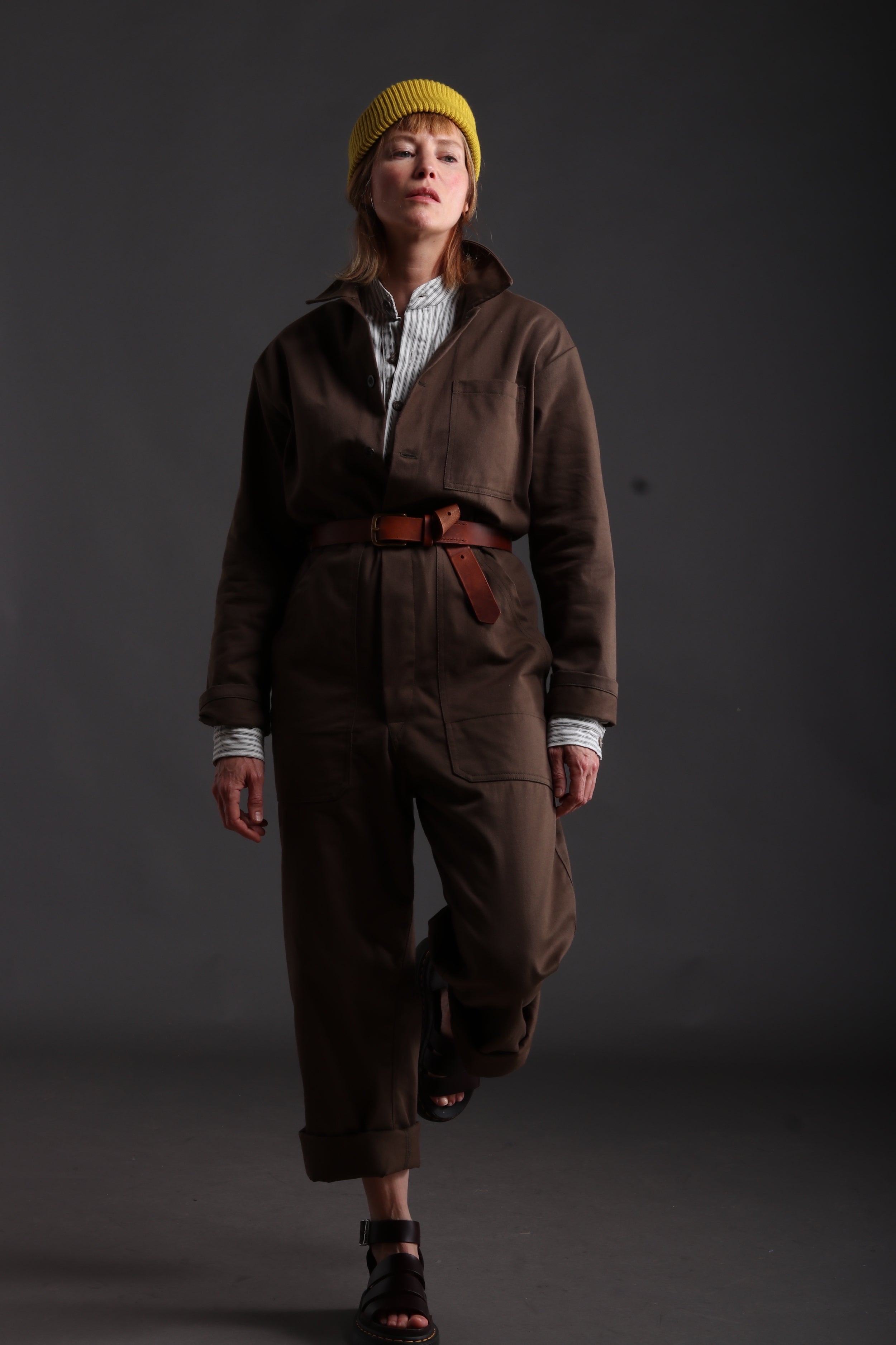 Sienna wears Carrier Company Boiler Suit in Olive Drill with Collarless Work Shirt in Ticking, Wool Hat and Chestnut Leather Belt
