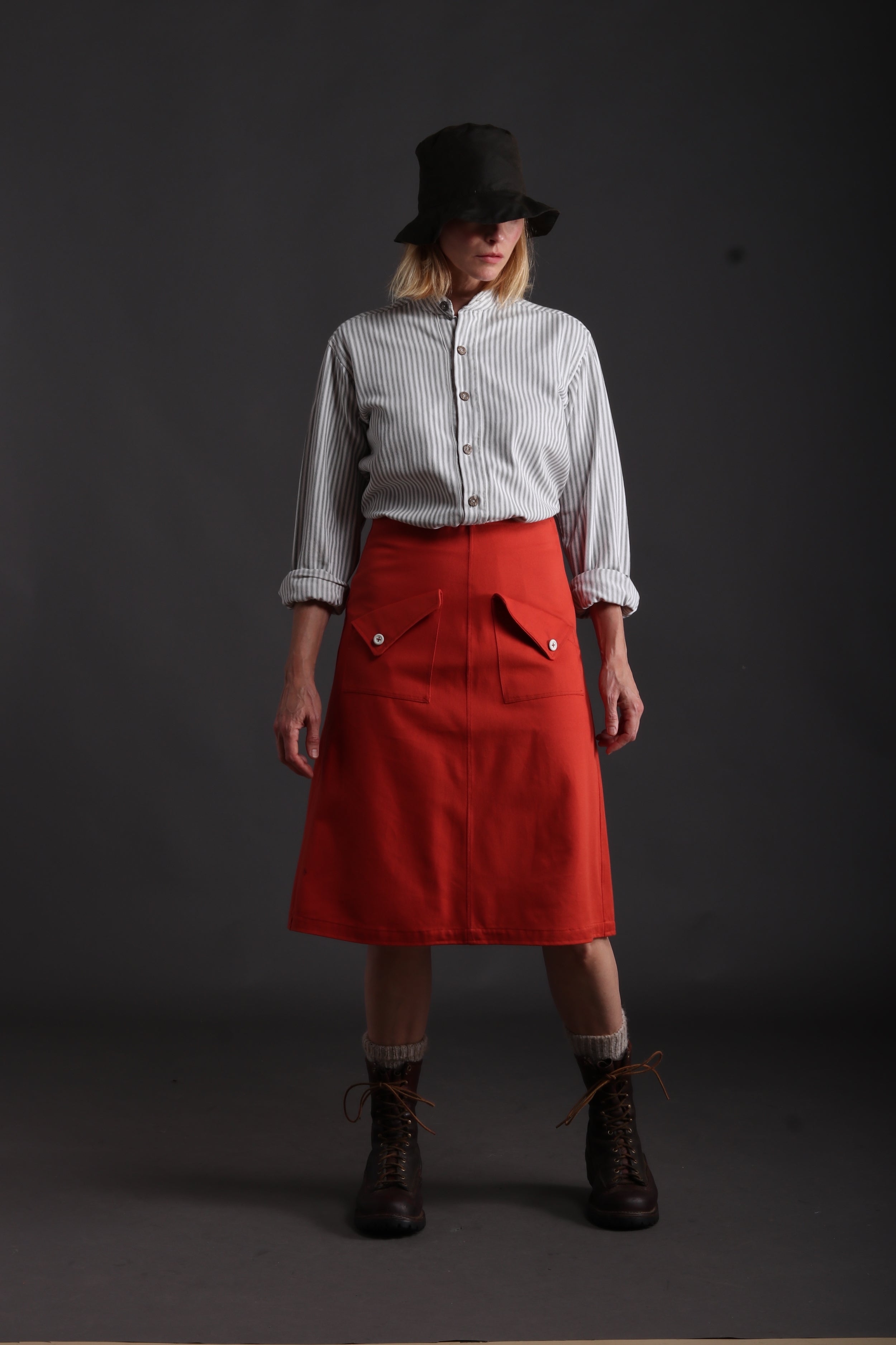 Woman wears Carrier Company Mum Skirt in Orange with Collarless Ticking Work Shirt and Rain Hat