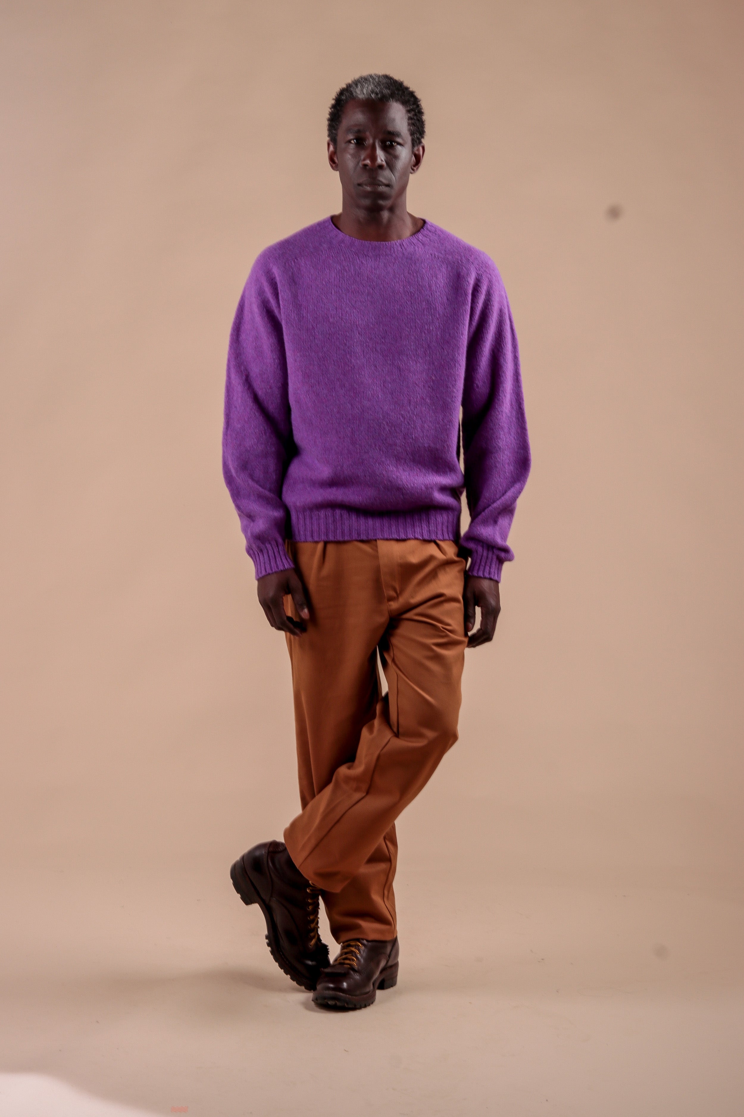 Man wears Carrier Company Shetland Lambswool Jumper in Allium with Classic Trouser in Tan