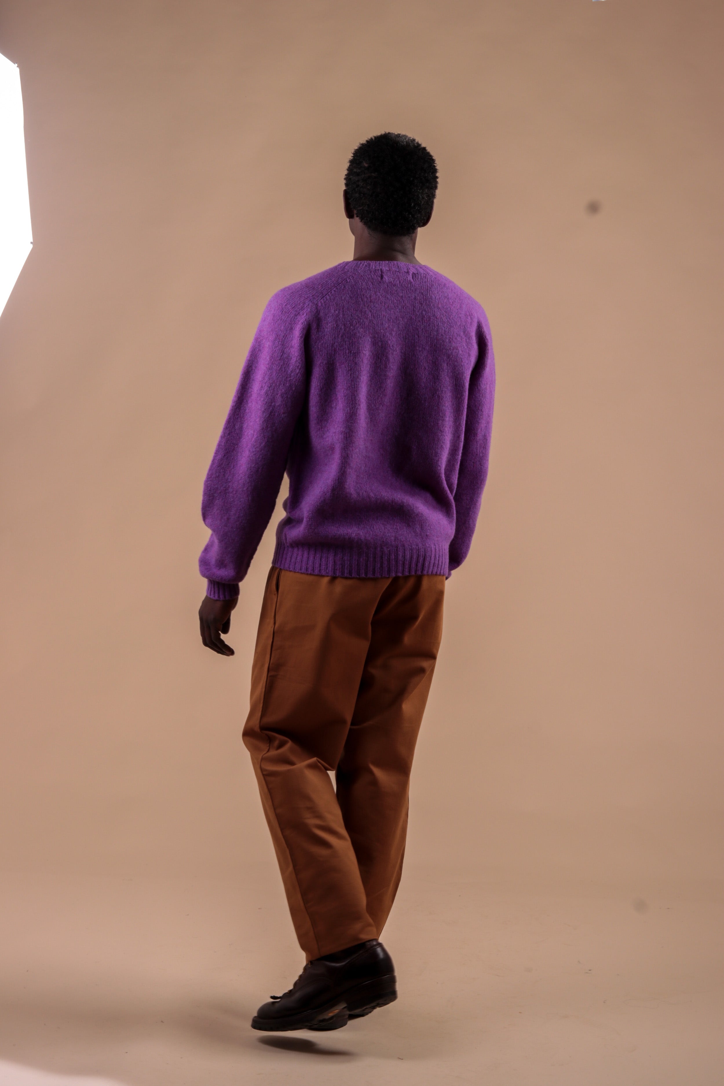 Man wears Carrier Company Shetland Lambswool Jumper in Allium with Classic Trouser in Tan