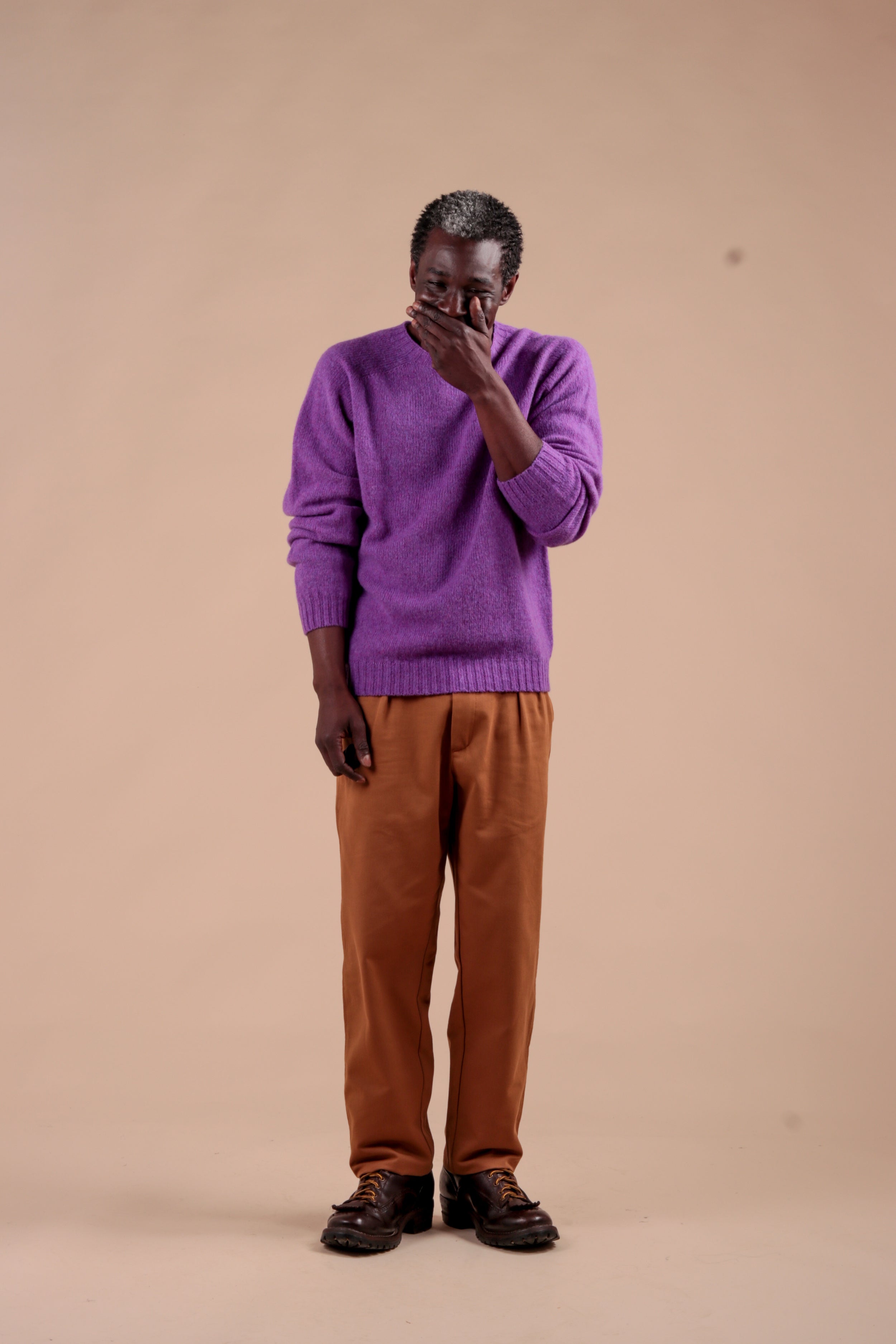 Man wears Carrier Company Shetland Lambswool Jumper in Allium with Classic Trouser in Tan
