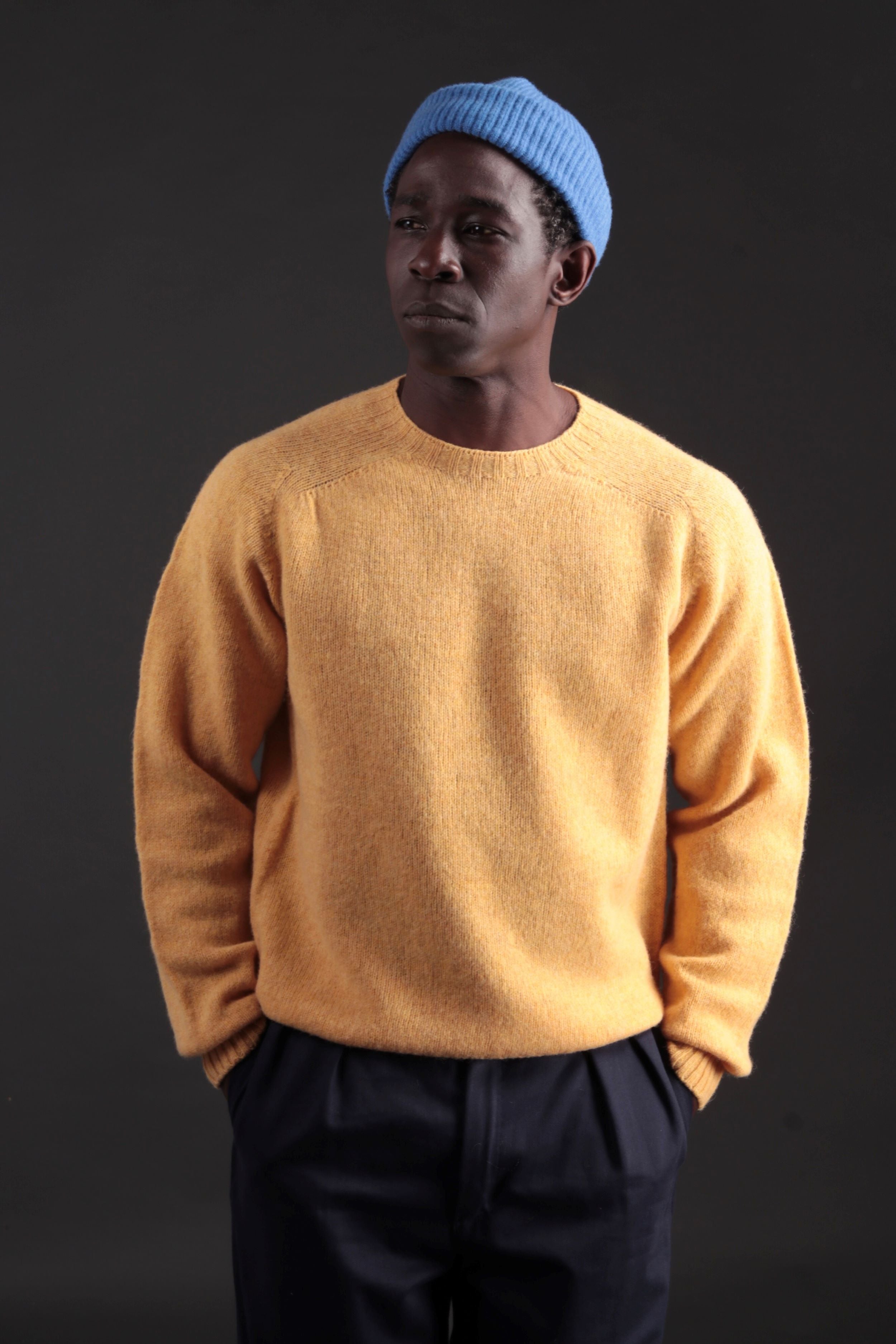 Man wearing Carrier Company Shetland Lambswool Jumper in Chamomile with Navy Classic Trousers and a Donegal Wool Hat