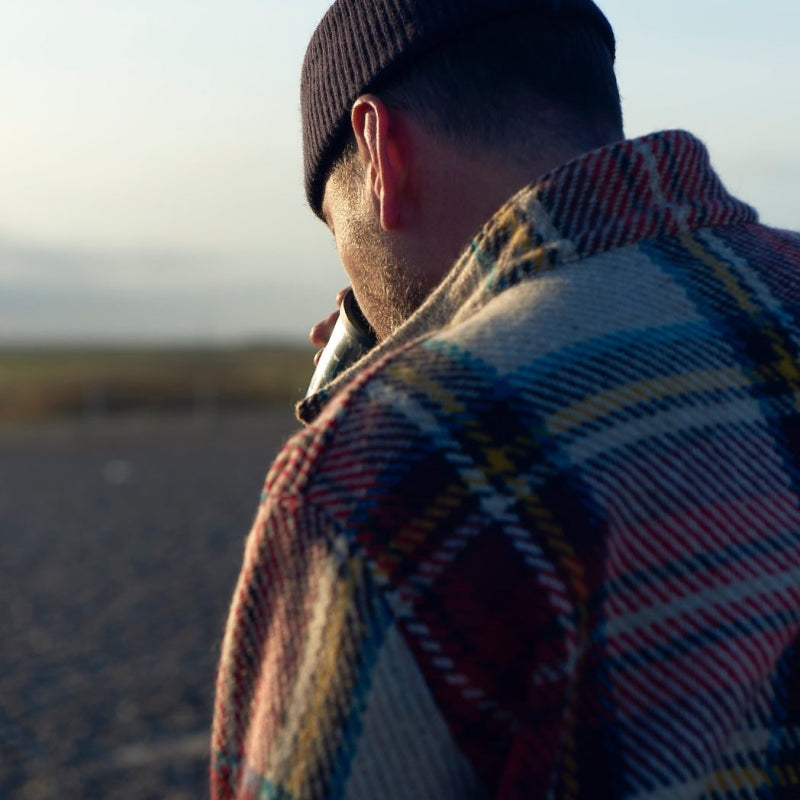 Man wearing the red Carrier Company Celtic Wool Jacket drinking in an outdoor location