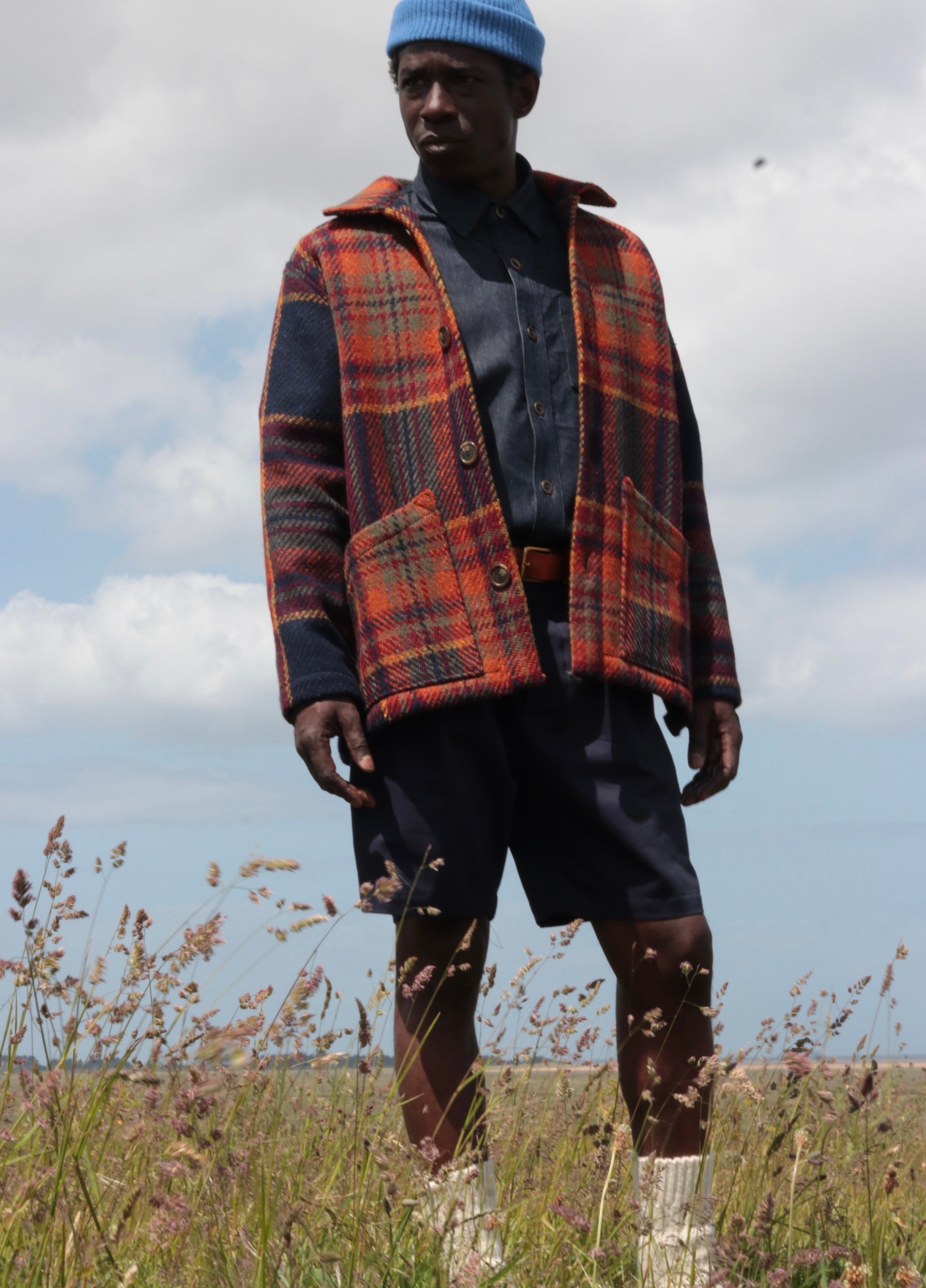 Man wears Celtic Wool Jacket in Navy and Rust with Denim Collar Shirt and Grandpa Shorts in Navy