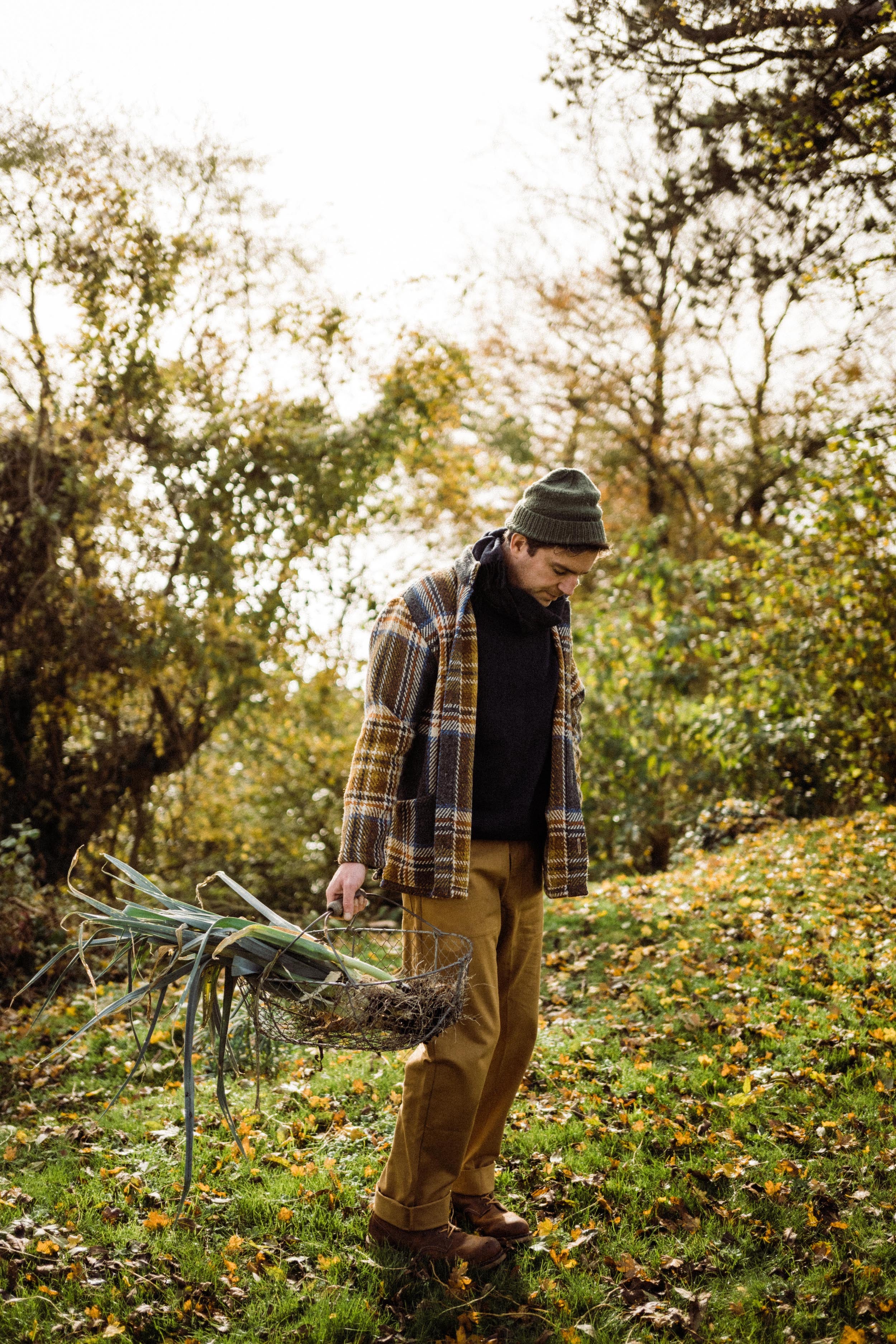 Man wears Carrier Company Celtic Wool Jacket in Slate & Russet with Traditional Guernsey and Men's Work Trouser in Tan