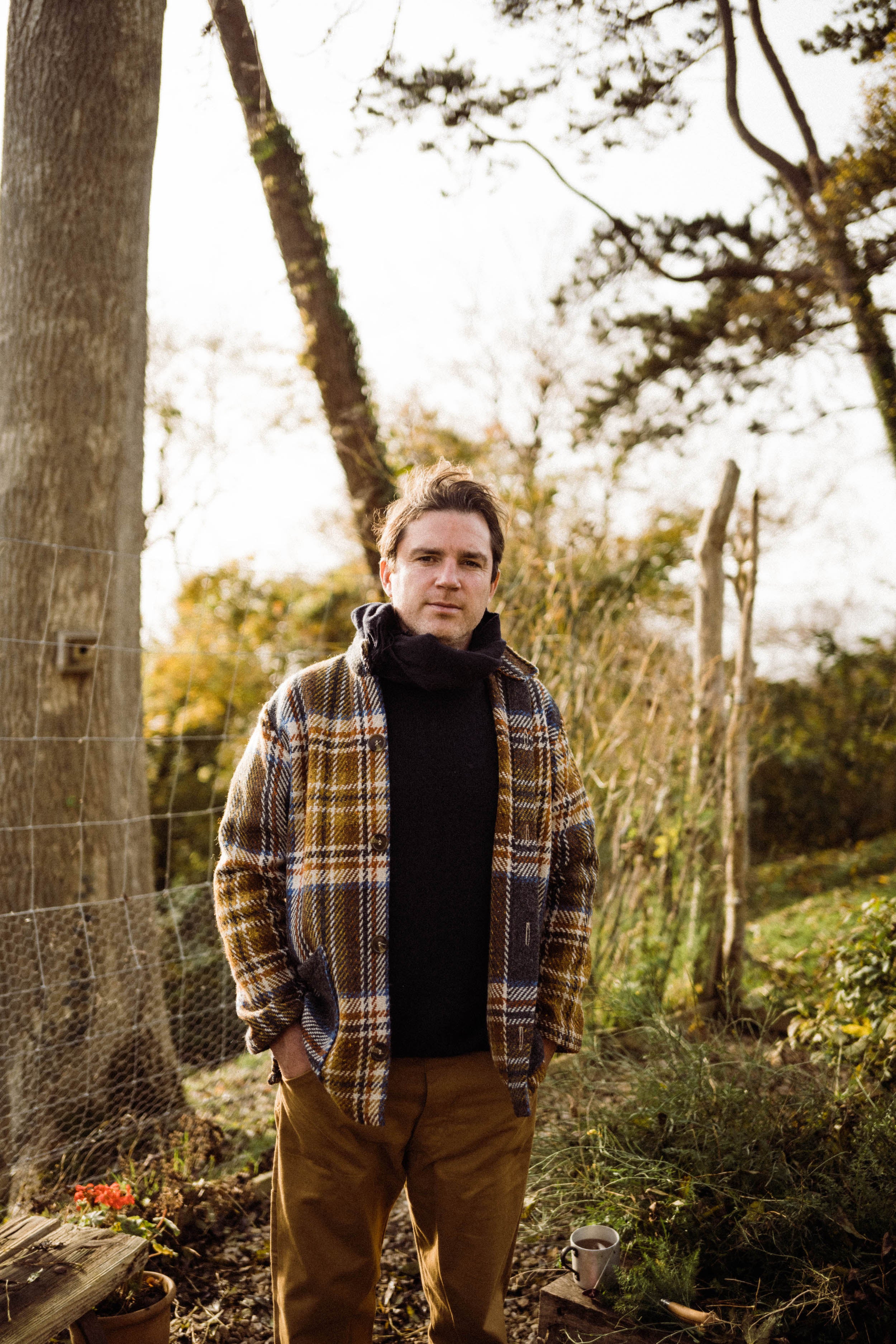 Man wears Carrier Company Celtic Wool Jacket in Slate & Russet with Traditional Guernsey and Men's Work Trouser in Tan