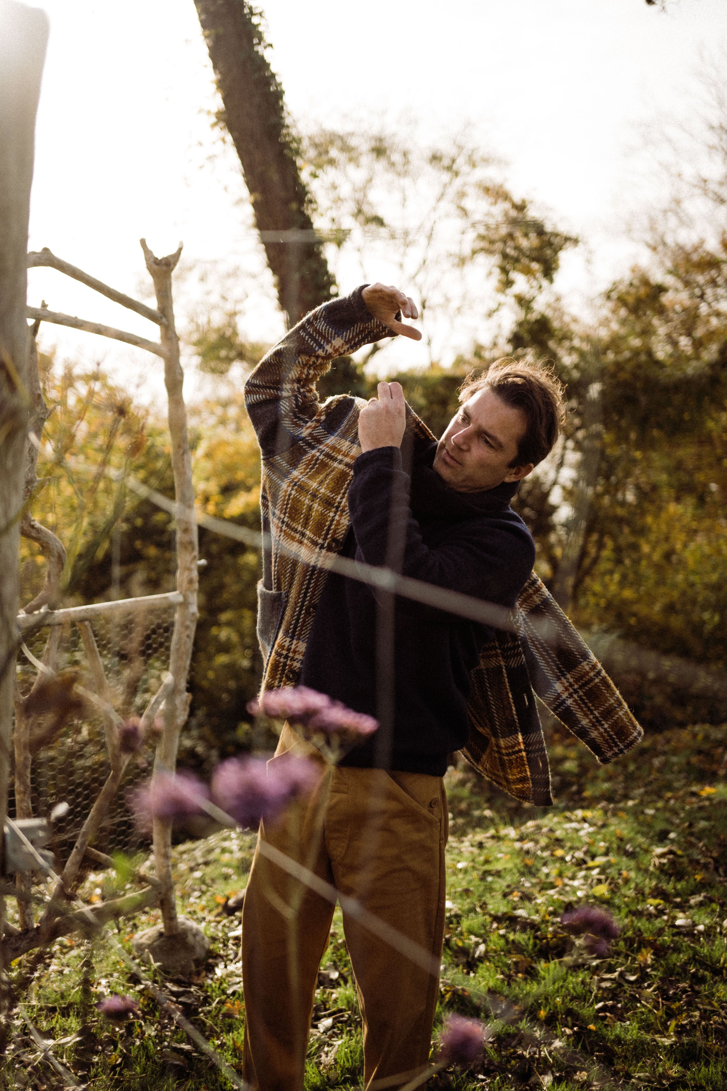 Man wears Carrier Company Celtic Wool Jacket in Slate & Russet with Traditional Guernsey and Men's Work Trouser in Tan