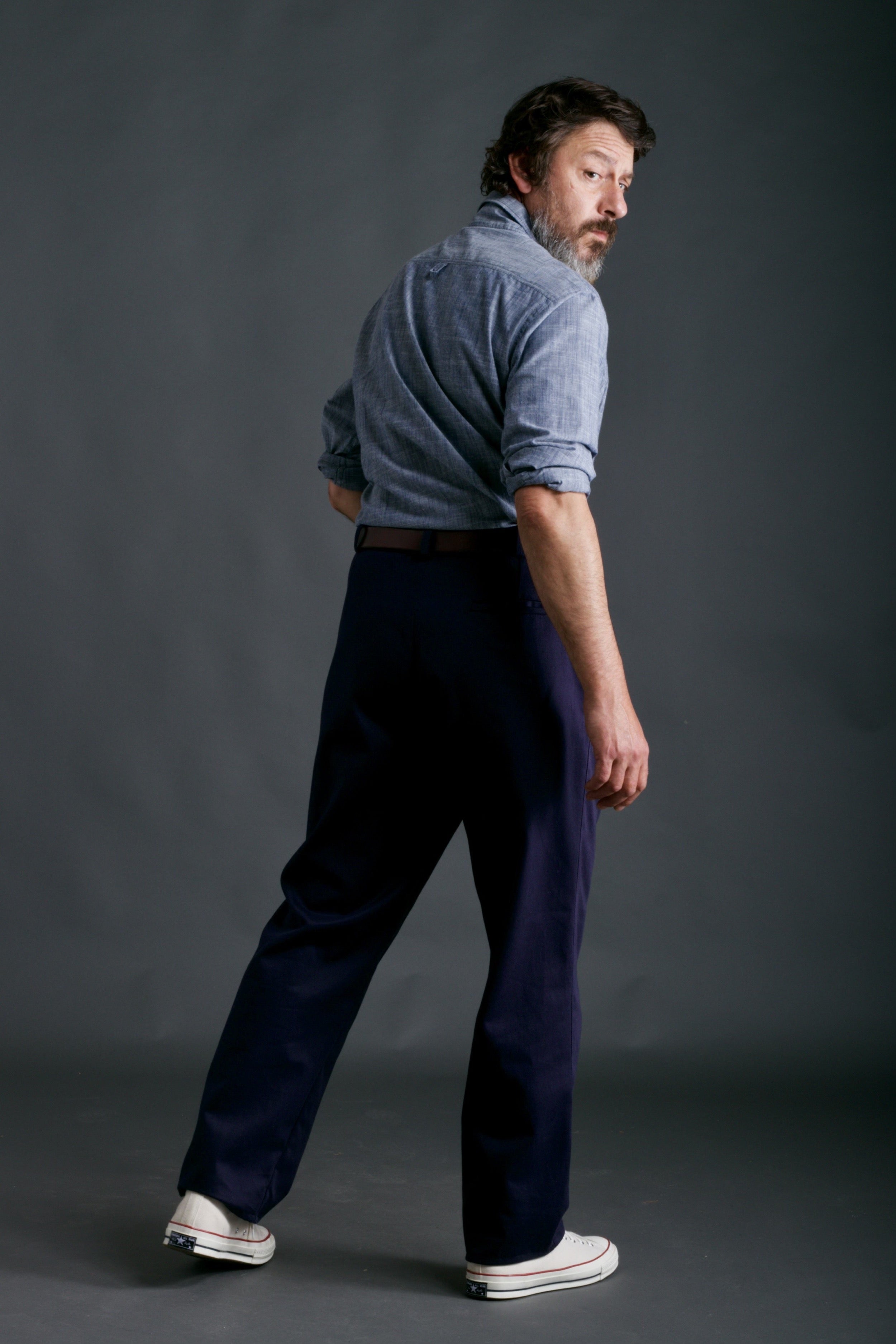 Man wears Carrier Company Classic Trouser in Navy Drill with Chambray Shirt