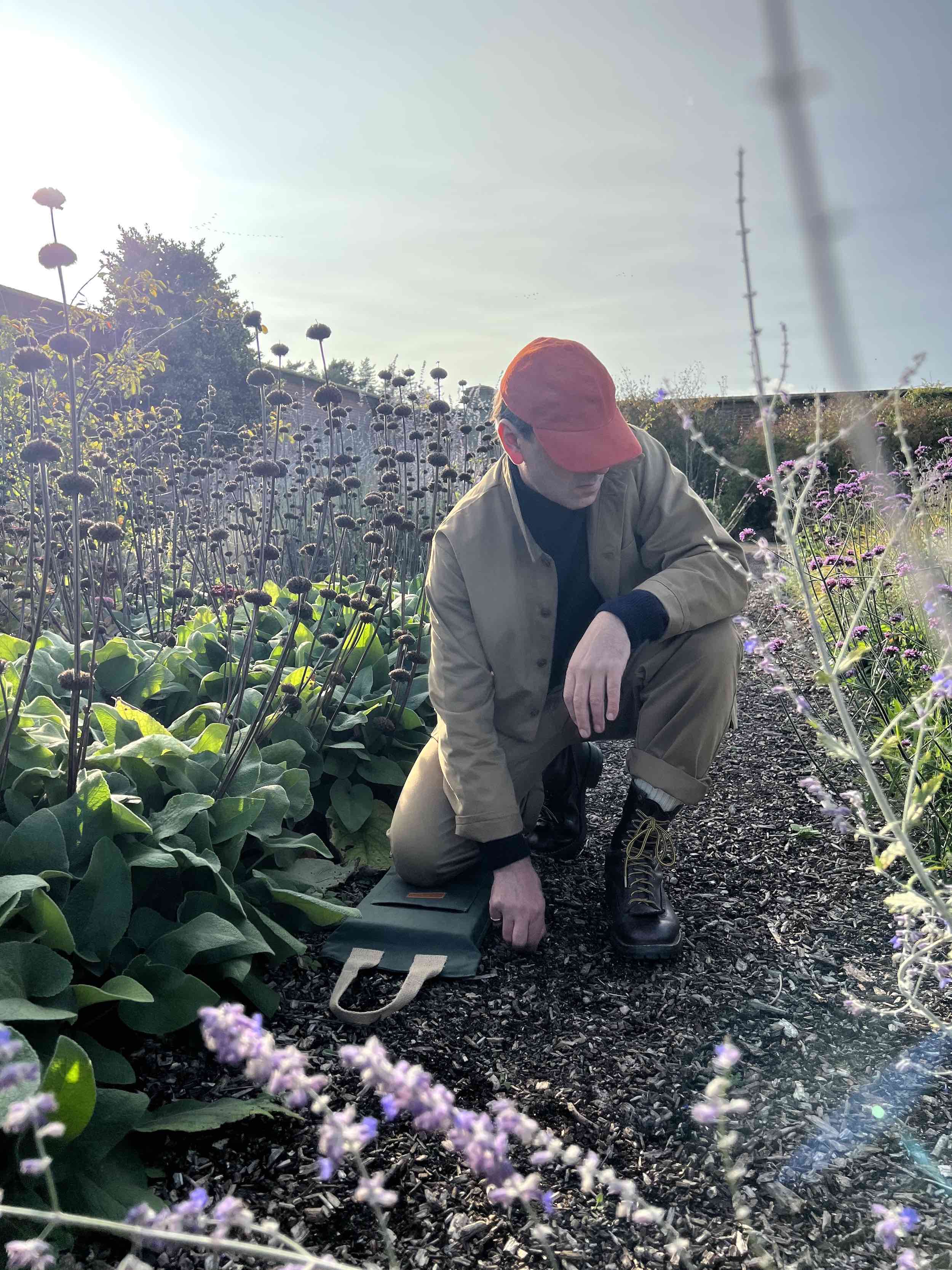 Enzo wears Carrier Company Merino & Cashmere Supersoft Roll Neck Jumper with Tan Norfolk Work Jacket and Corduroy Cap