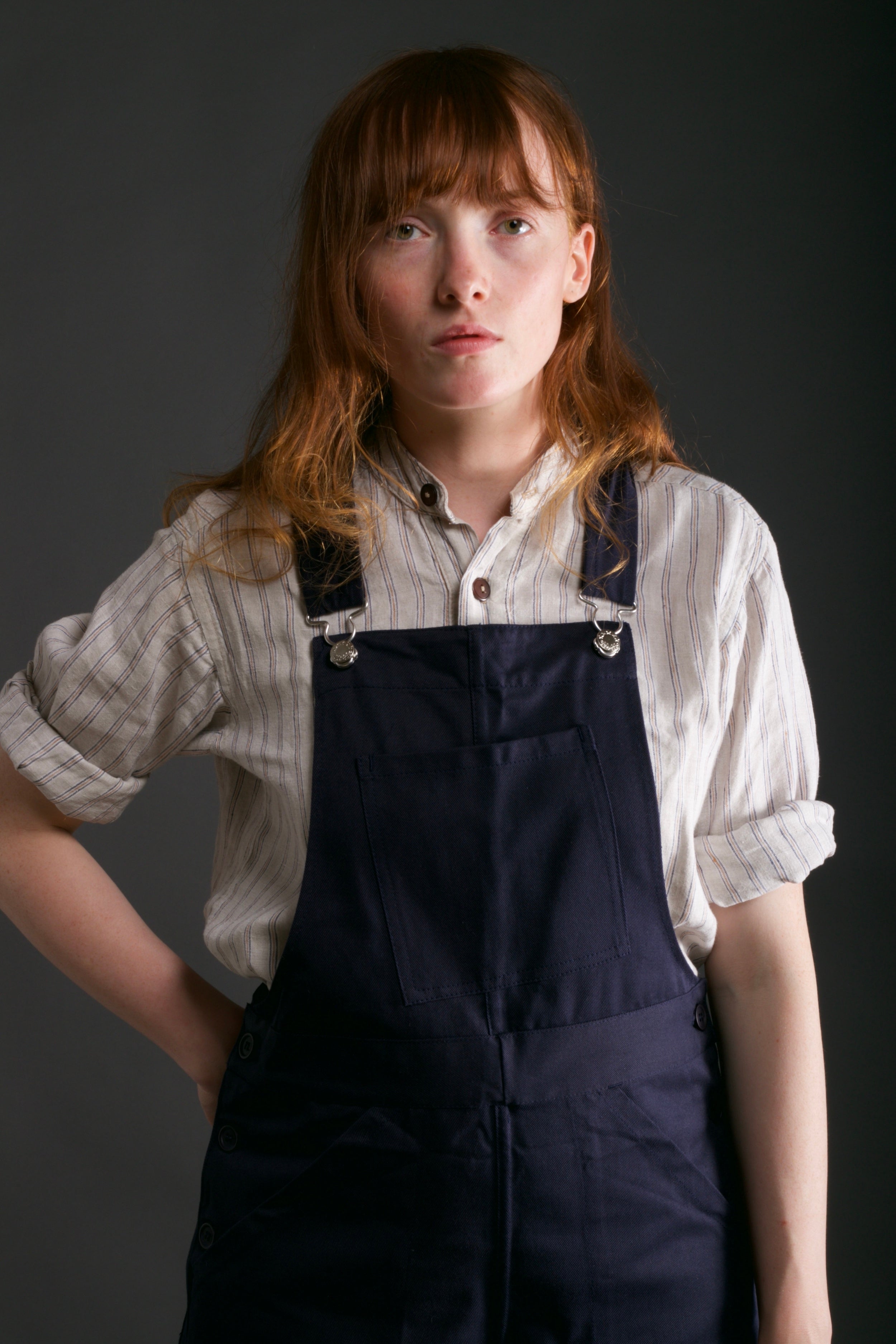 Woman wears Carrier Company Women's Dungarees in Navy with Linen Collarless Work Shirt