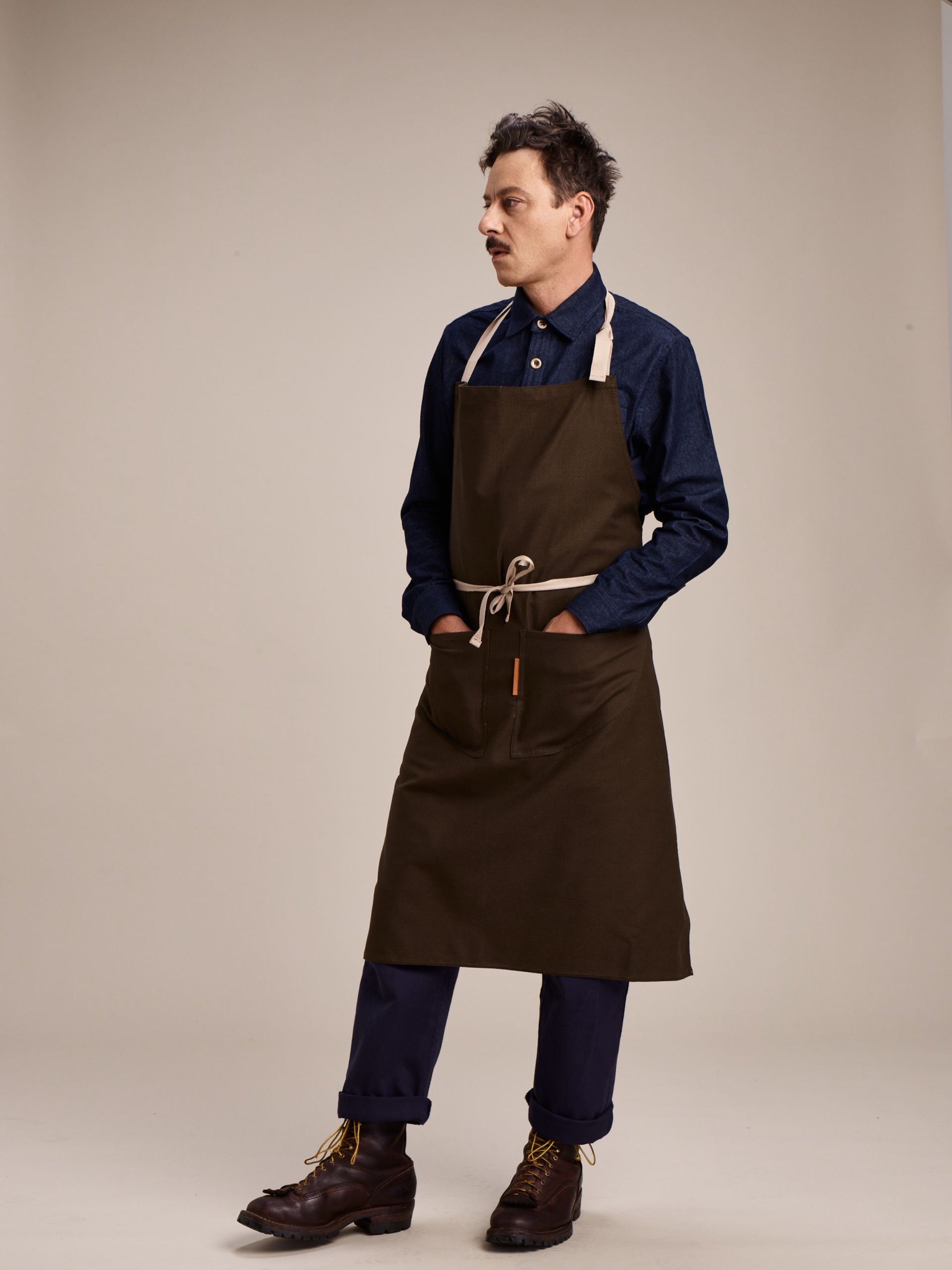 Man wears Carrier Company Long Apron in Olive