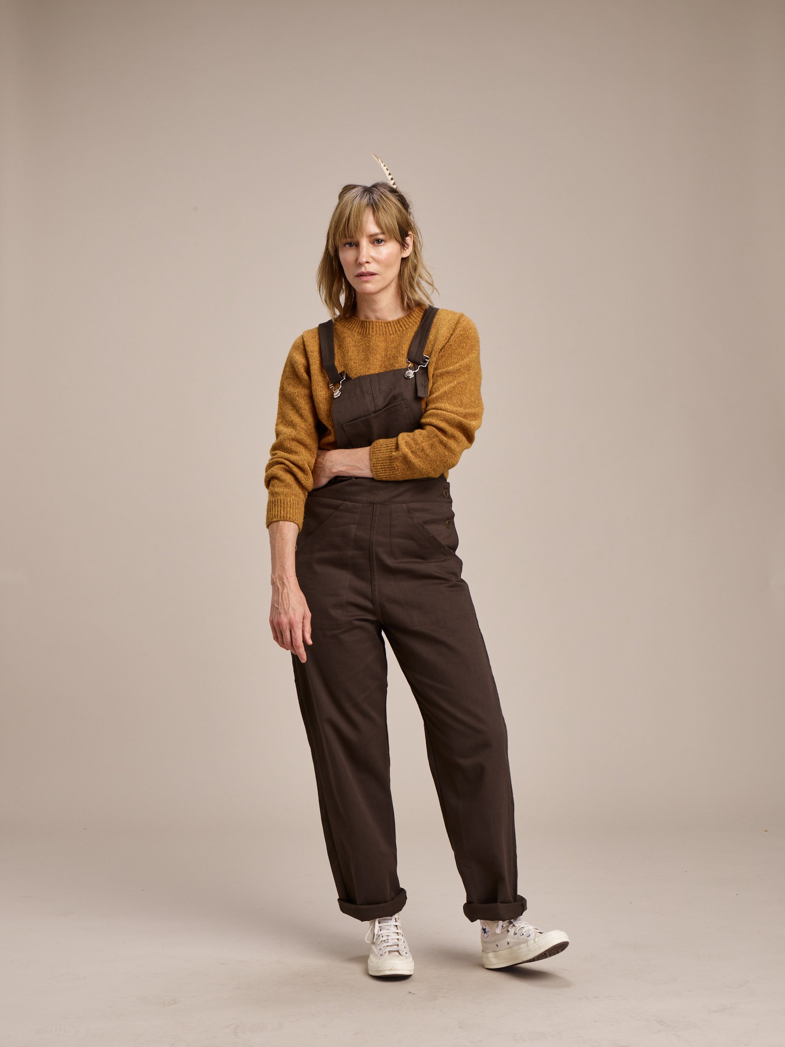 Woman wears Carrier Company Women's Dungarees in Olive with Shetland Lambswool Jumper