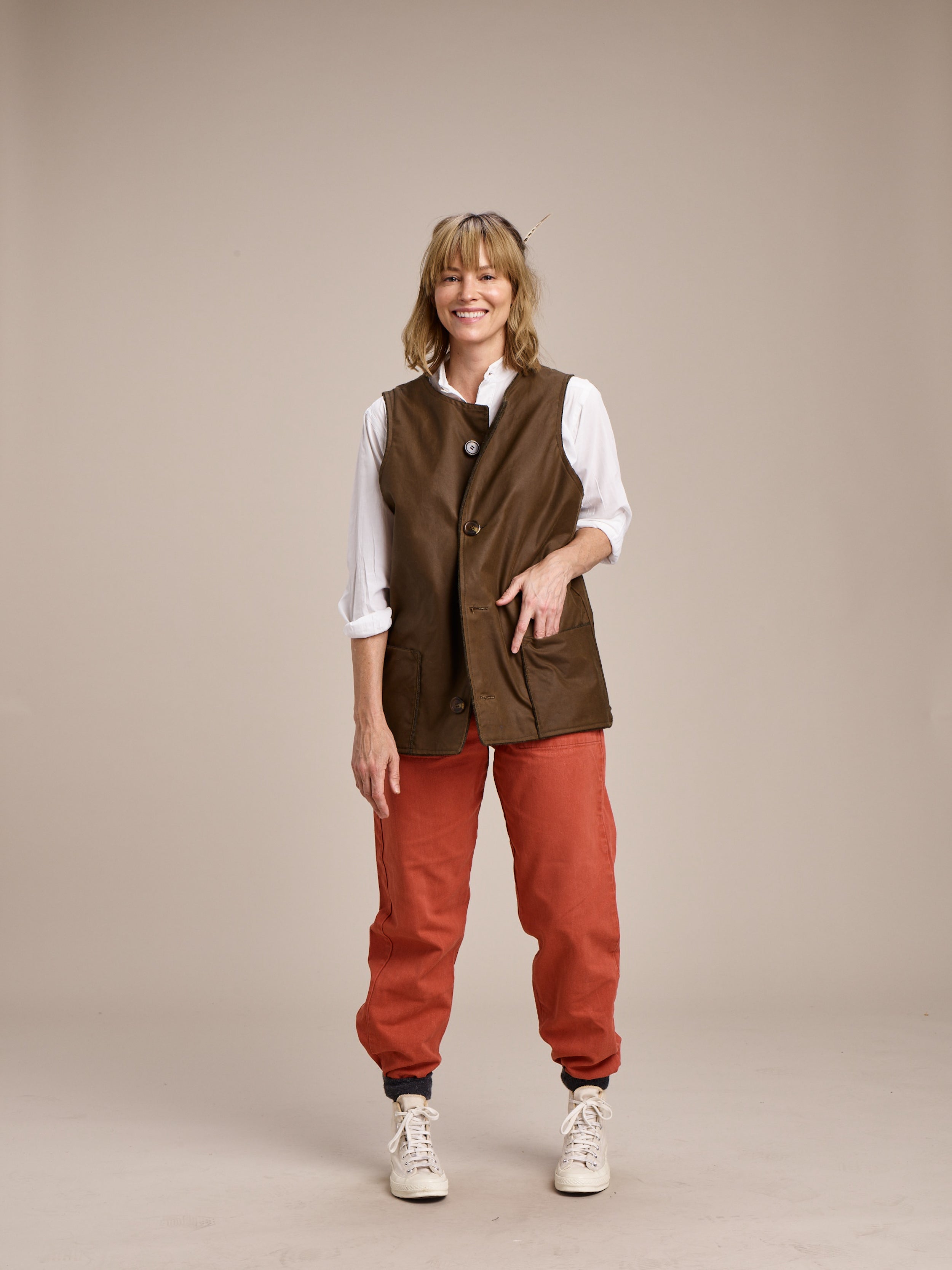 Woman wears Carrier Company Women's Work Trousers in Orange with Wax Jerkin and Lightweight Collarless Shirt