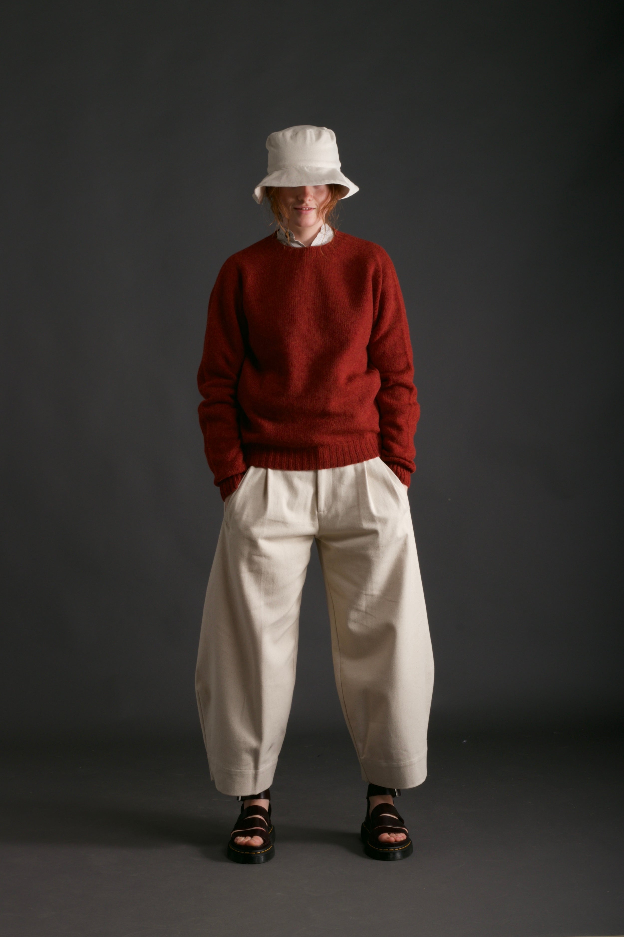 Woman wears Carrier Company Dutch Trouser in Seeded Denim with Shetland Lambswool Jumper and Cotton Sun Hat