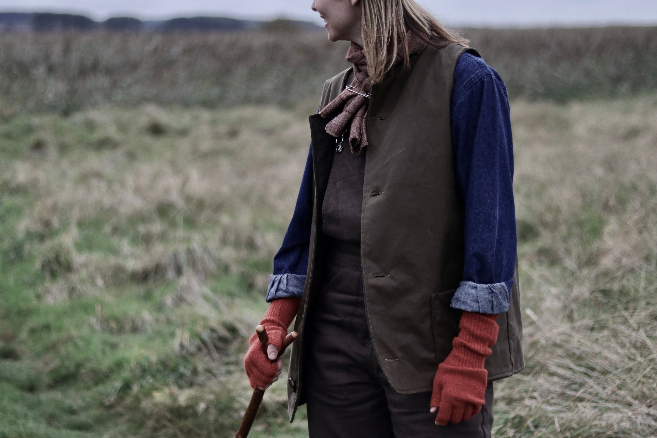 Woman wears Carrier Company Women's Dungarees in Olive with Norfolk Jerkin and Denim Work Shirt