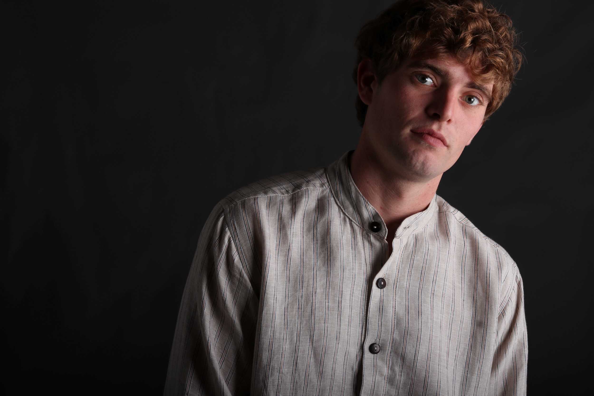 Man wears Carrier Company Collarless Shirt in Natural Linen with Navy and Terracotta Stripe