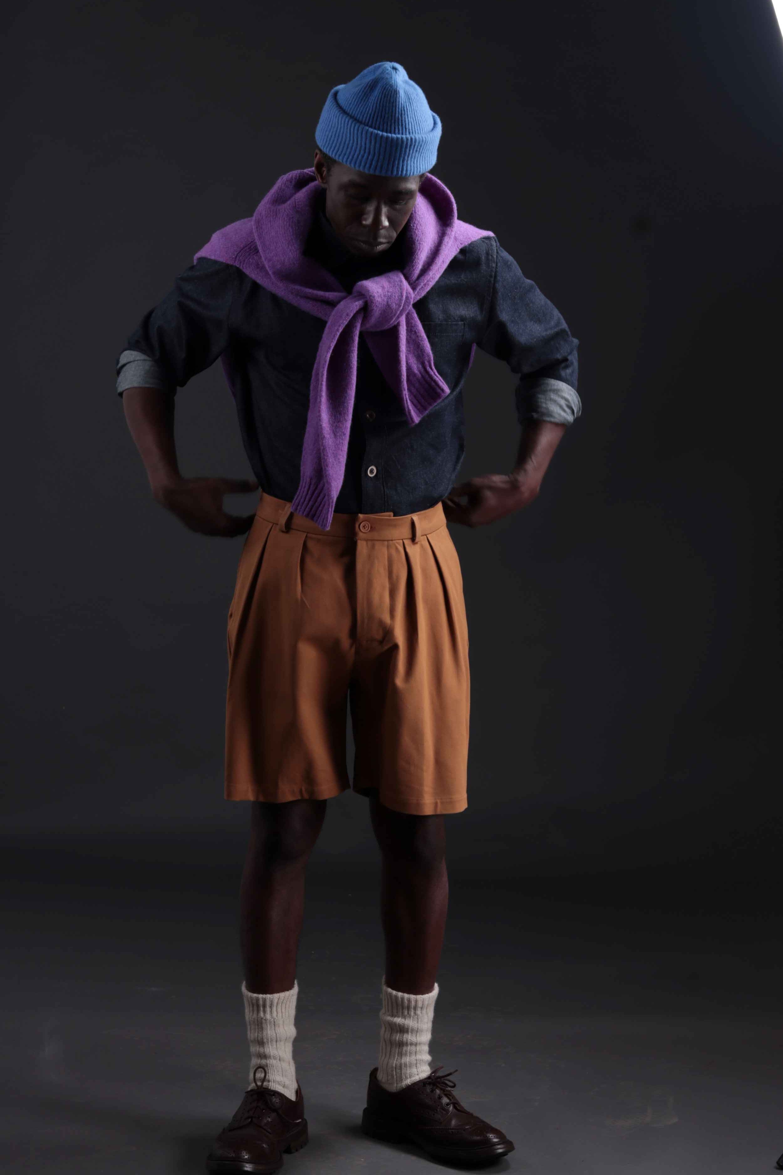 Abdul wears Carrier Company Grandpa Shorts in Tan with Denim Collar Shirt and Shetland Lambswool Jumper in Amethyst
